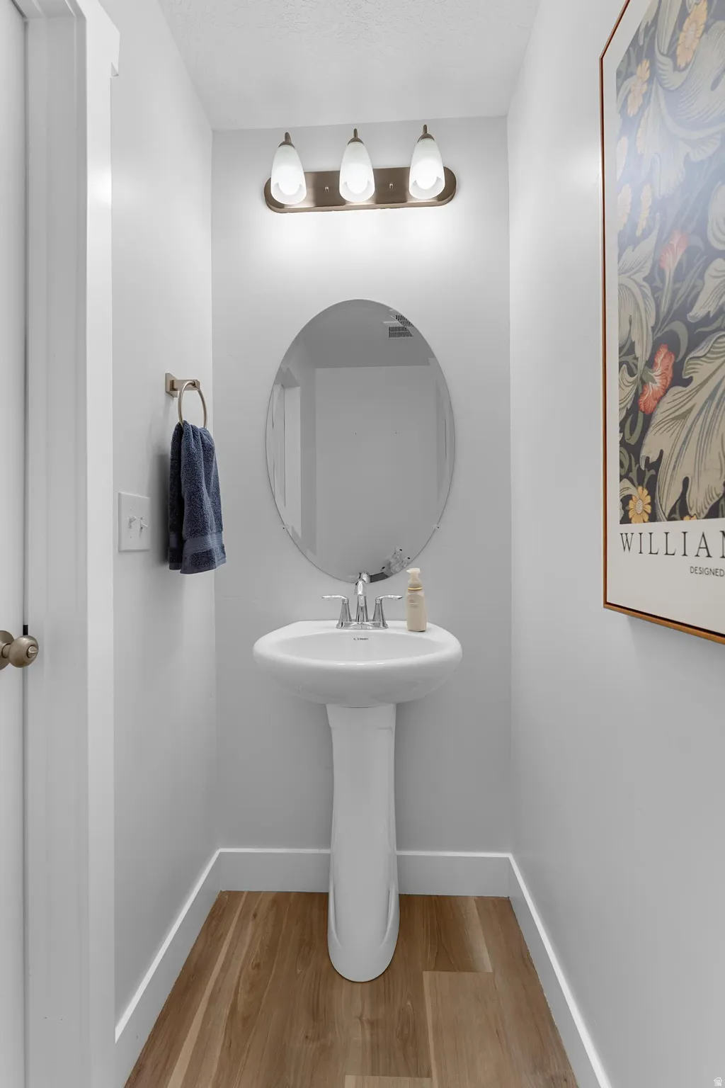 Main floor half bathroom featuring light wood-style flooring and baseboards