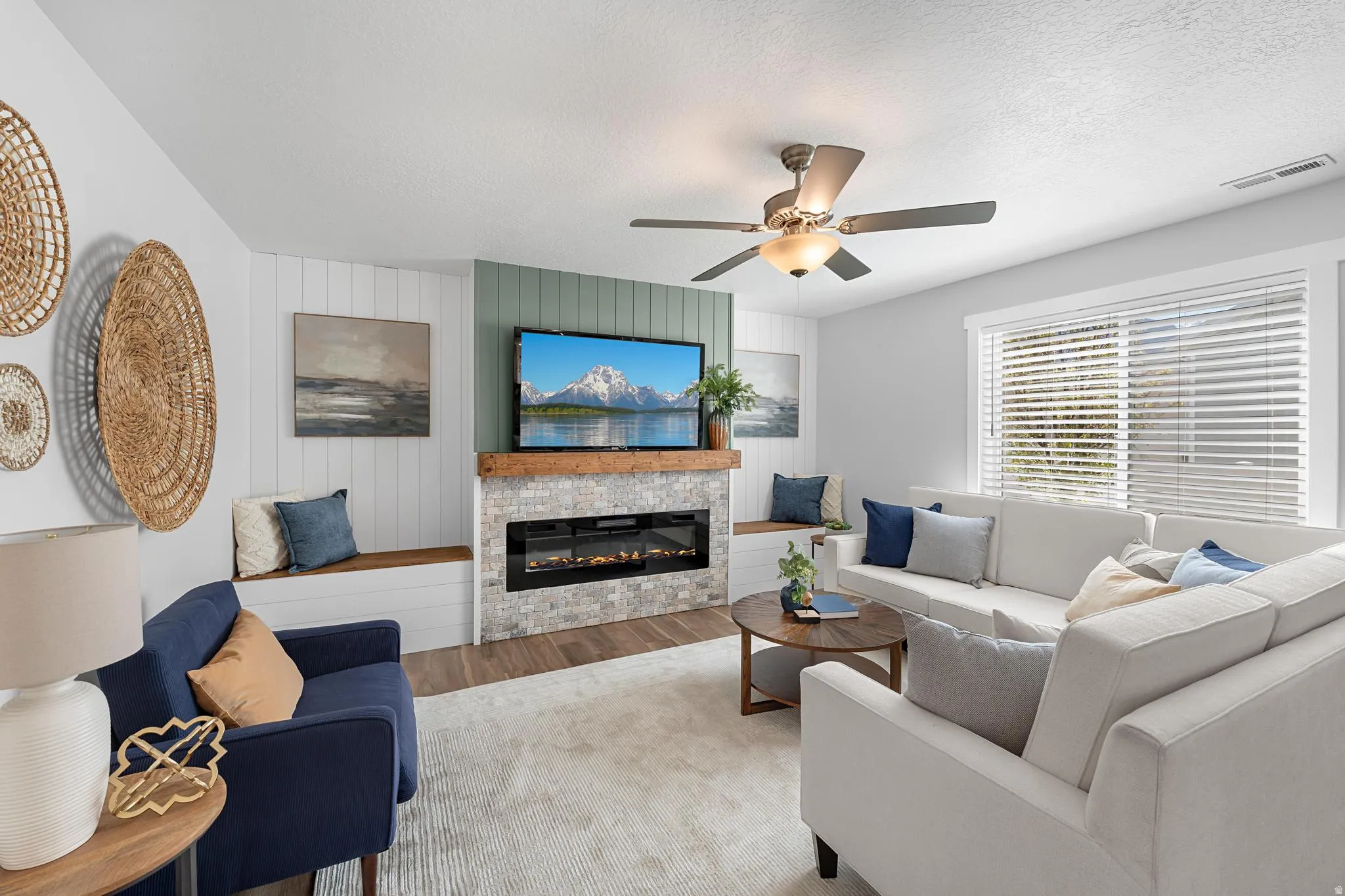 Living area featuring wood finished floors, a fireplace, a ceiling fan, and a textured ceiling