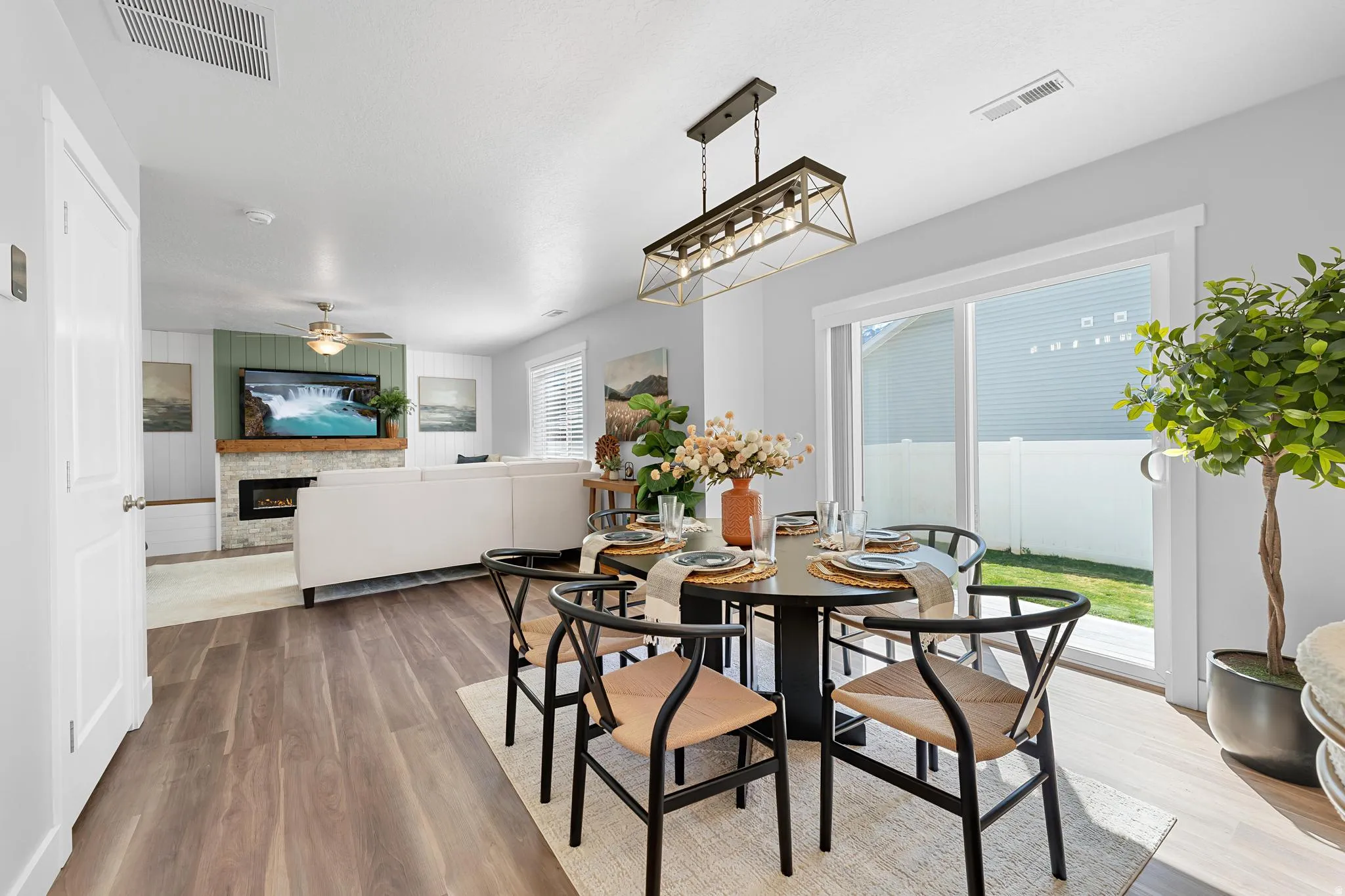 Dining room featuring a glass covered fireplace, wood finished floors, a ceiling fan, and wood walls