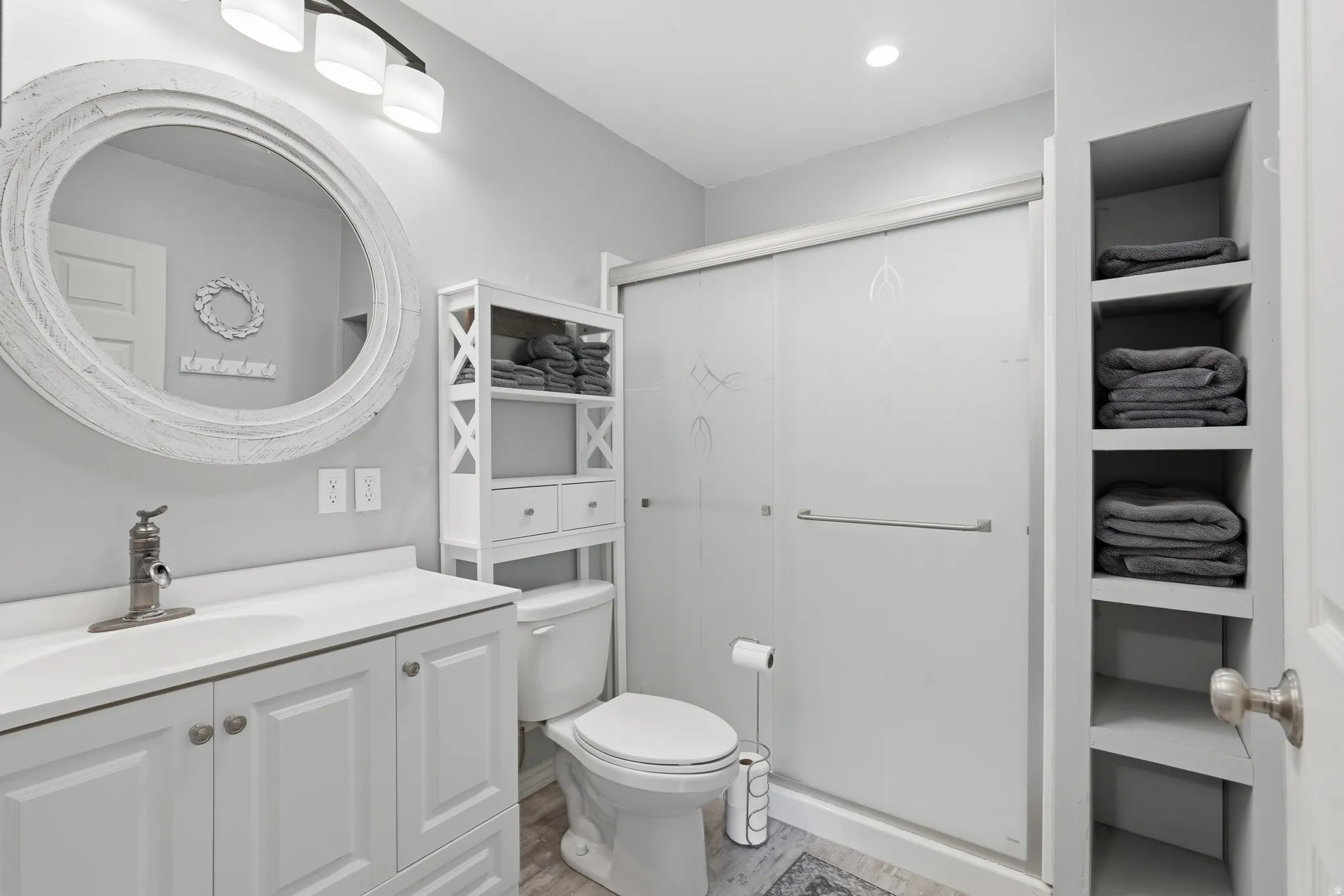 Full bathroom featuring vanity, a shower stall, and light wood-style flooring