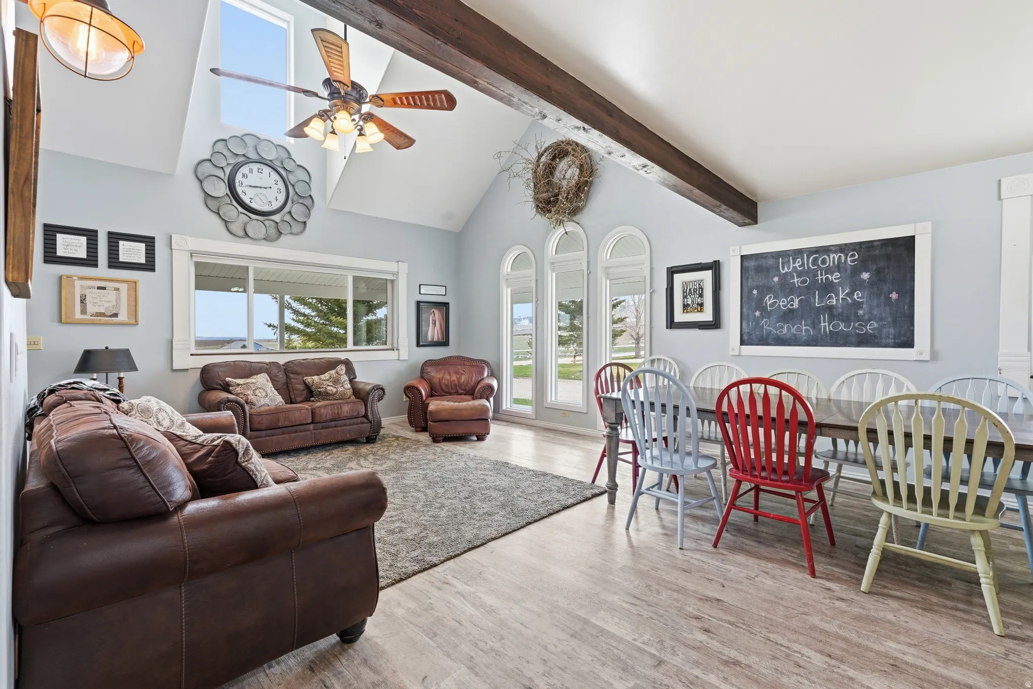 Living room with light wood-style flooring, a ceiling fan, and lofted ceiling