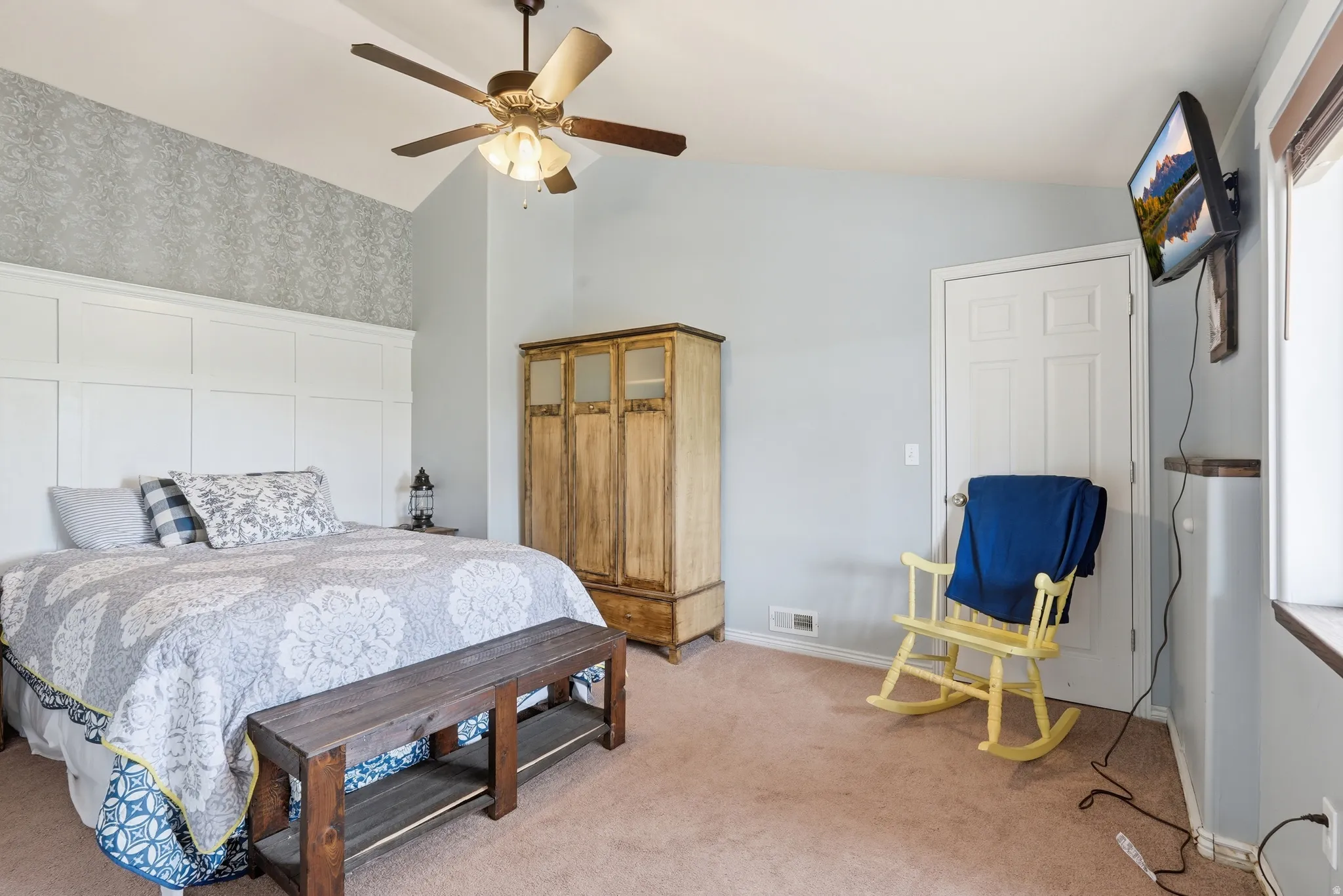 Bedroom featuring wallpapered walls, vaulted ceiling, a ceiling fan, and light colored carpet