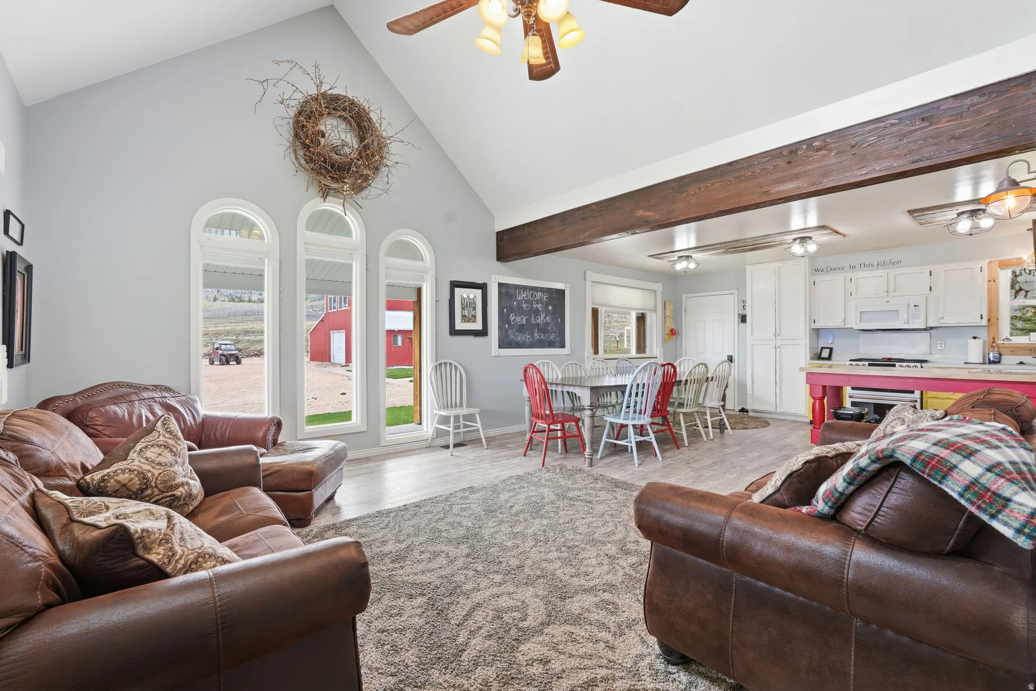Living area featuring ceiling fan, light wood finished floors, and vaulted ceiling