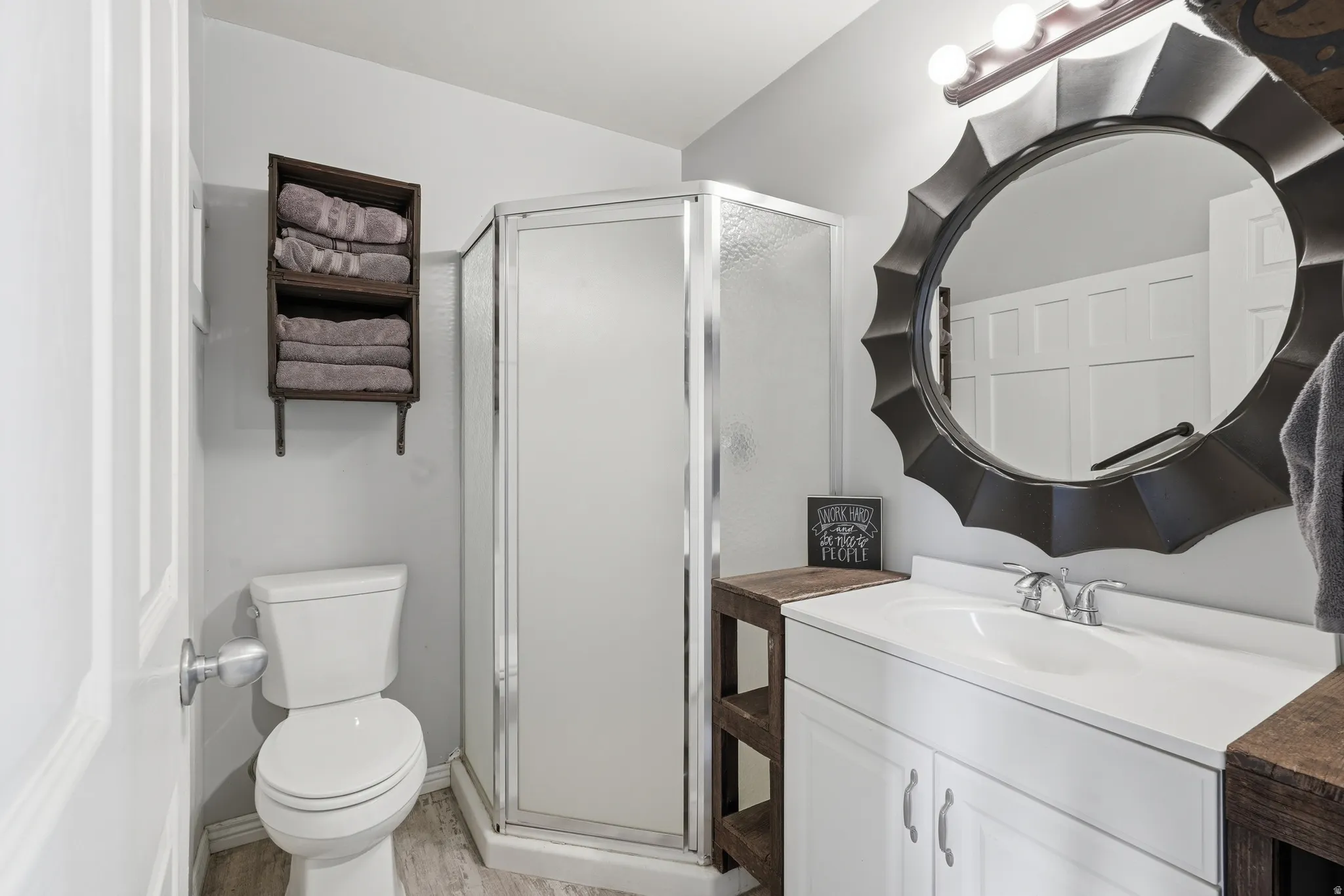Bathroom featuring vanity, a stall shower, and light wood-type flooring