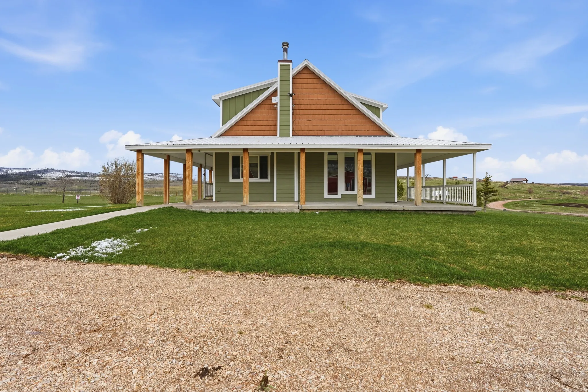 Rear view of house featuring a large porch, a metal roof, a yard, and a chimney