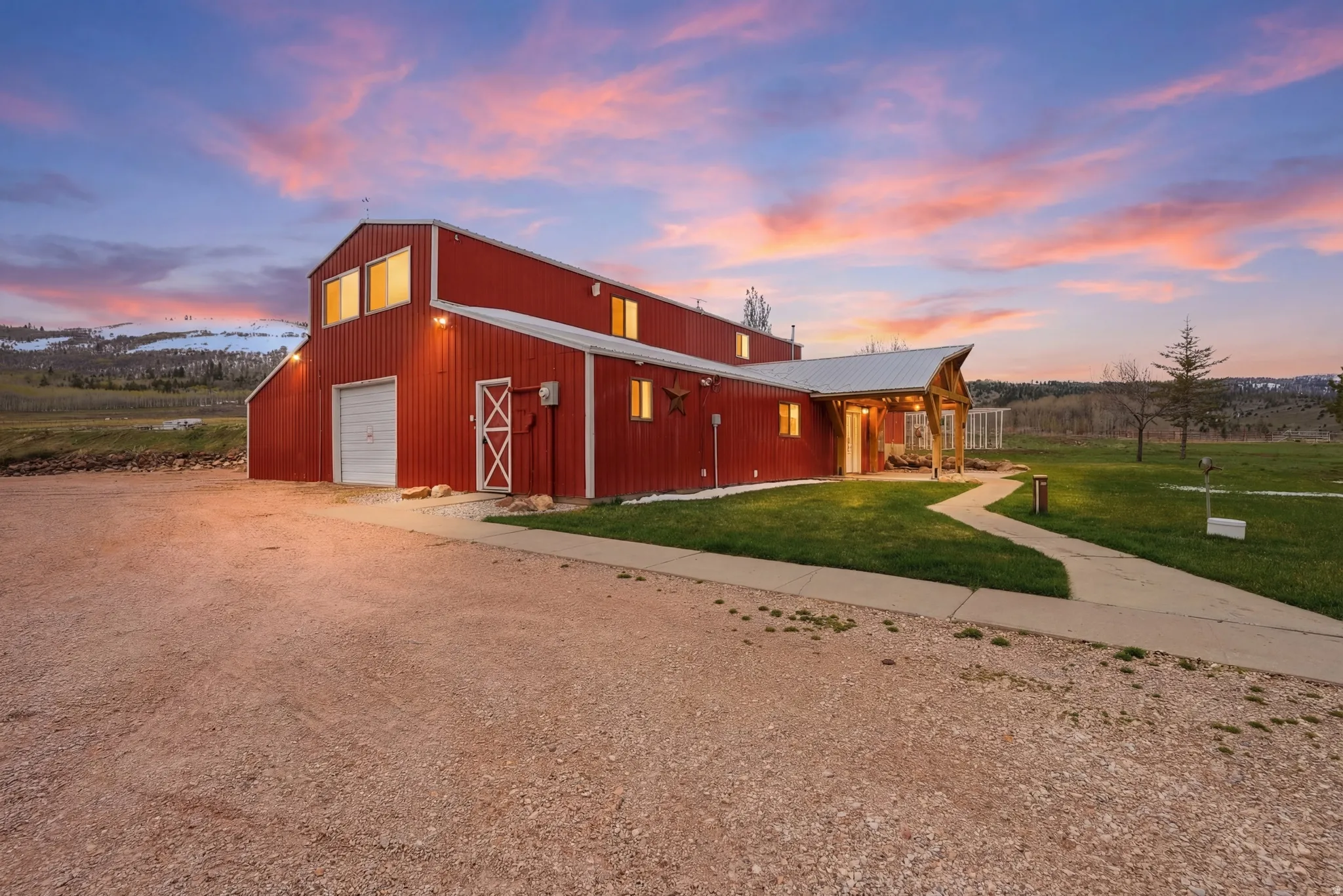 View of front of property featuring a front lawn, dirt driveway, a garage, and an outbuilding