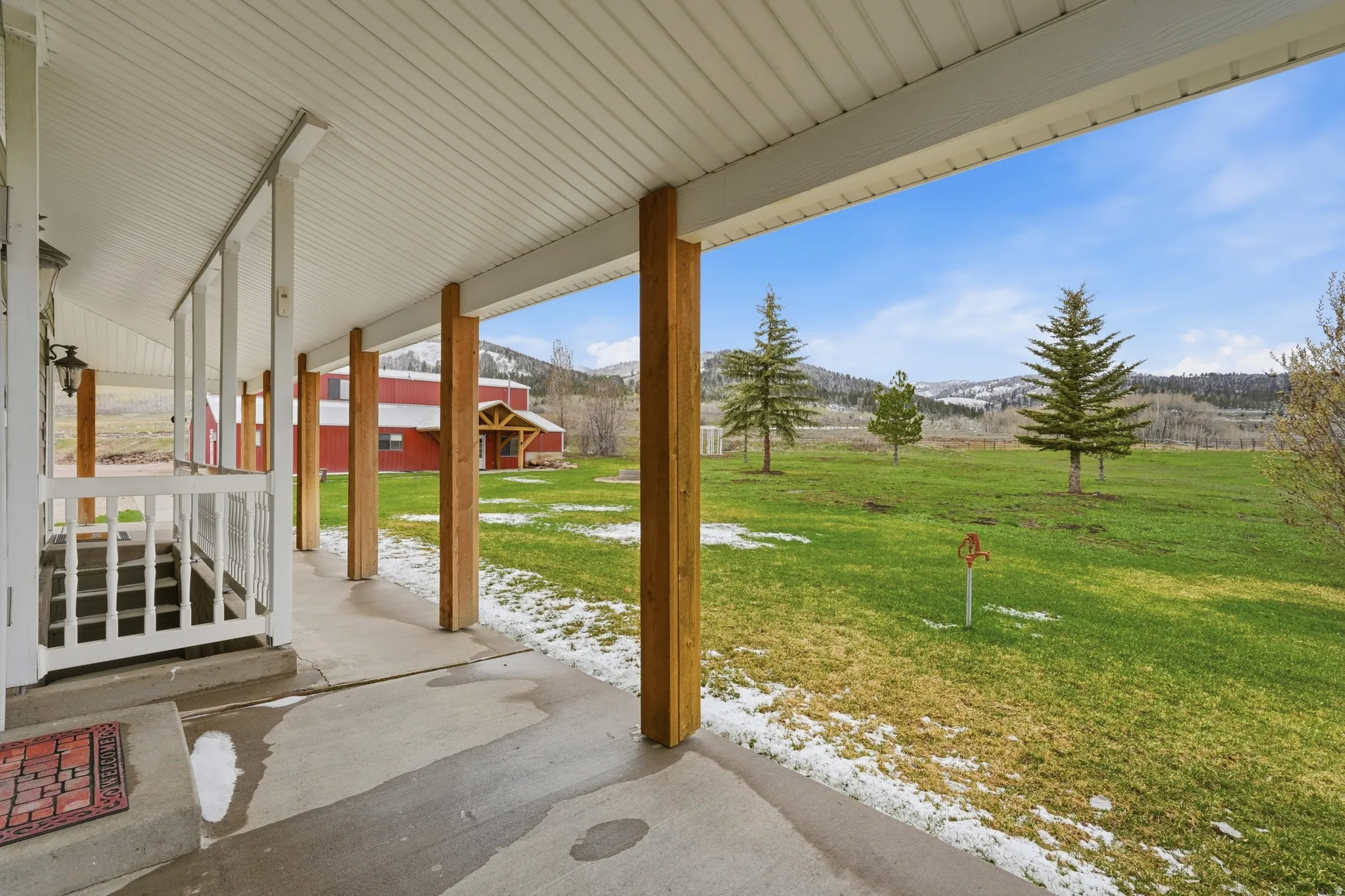 Snow covered patio featuring a lawn, covered porch, and a mountain view