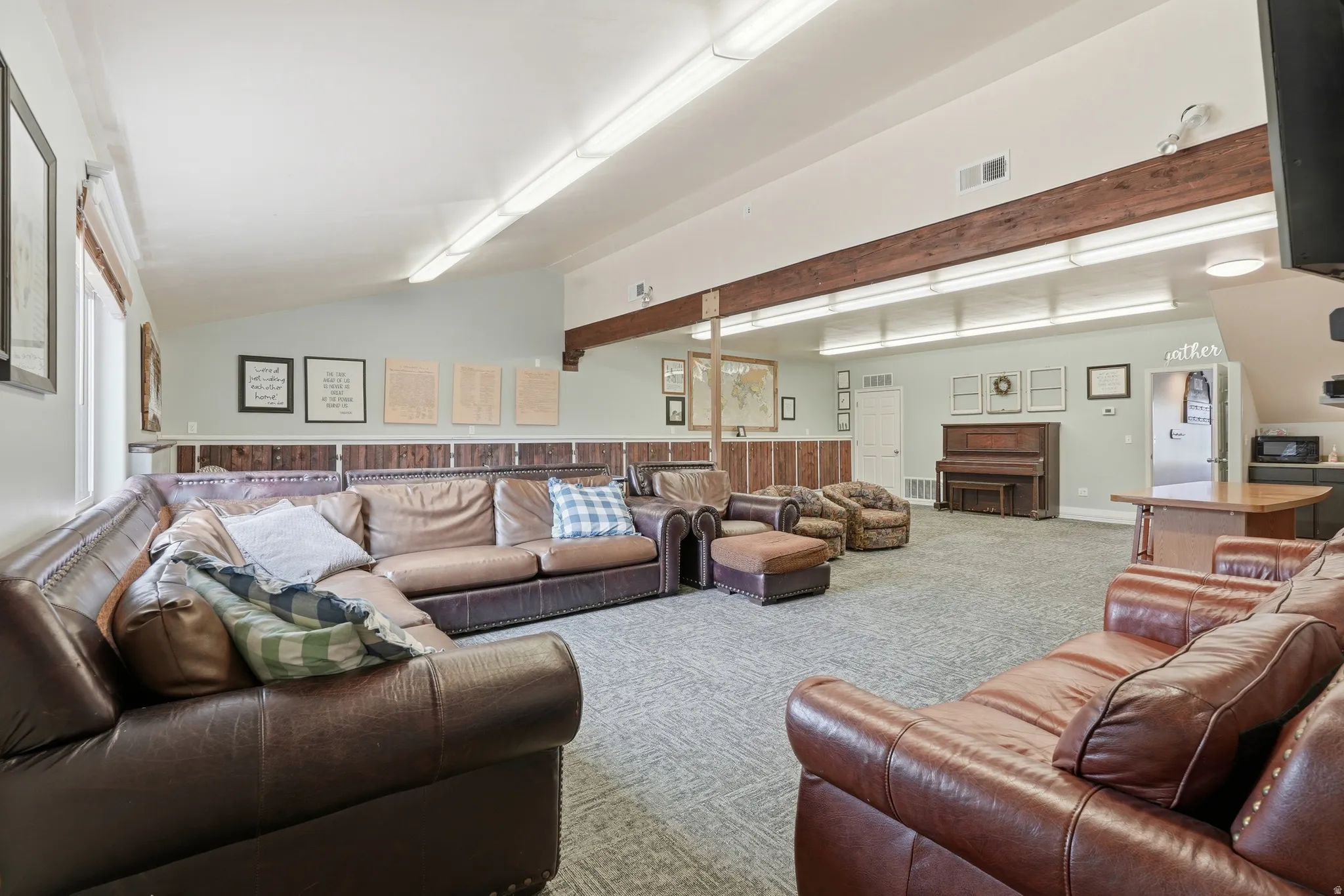 Carpeted living area with vaulted ceiling with beams