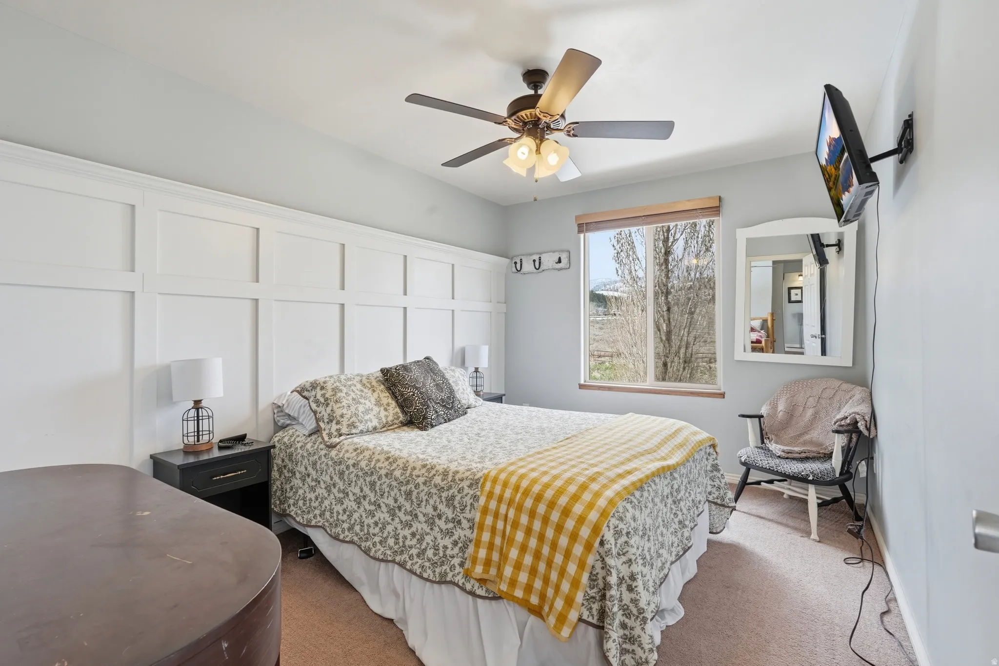 Bedroom with carpet floors, a ceiling fan, and a decorative wall