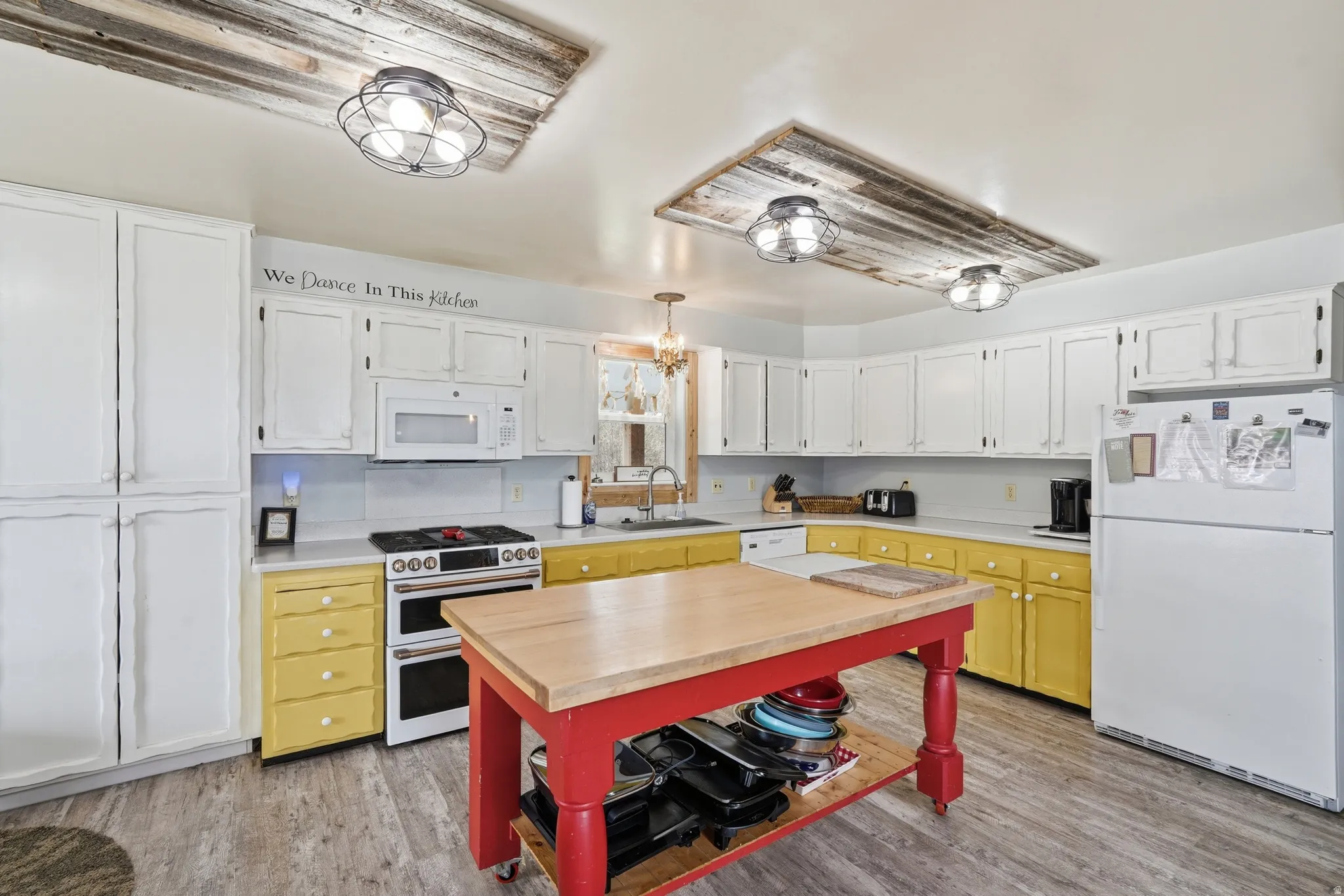 Dual tone kitchen with white appliances, light wood finished floors, two tone color scheme, and wood counters
