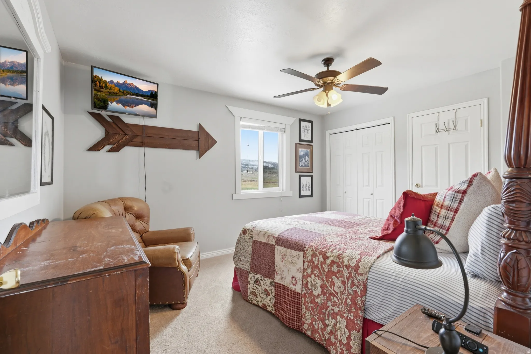 Bedroom with ceiling fan, light carpet, and two closets