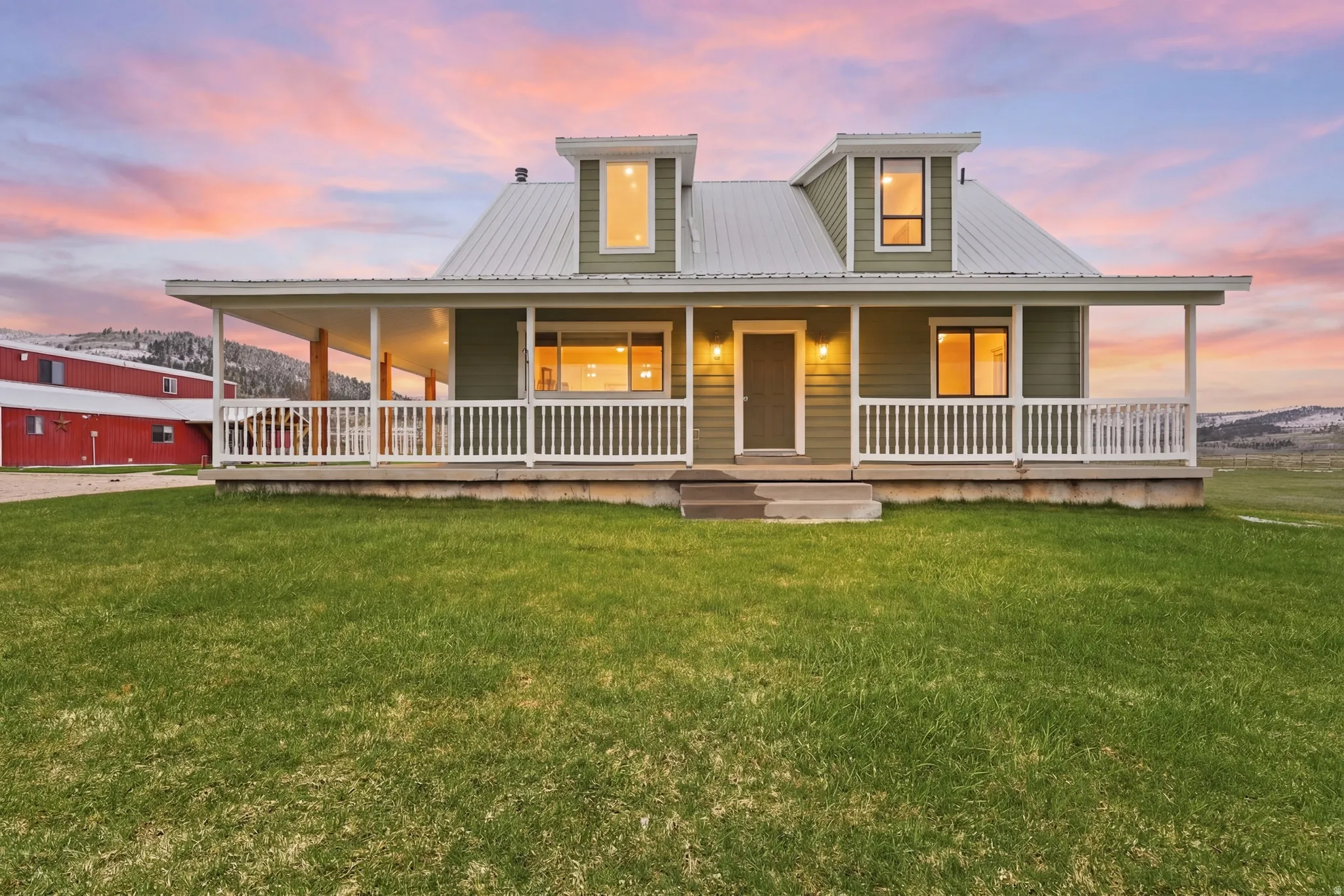 Farmhouse-style home with a porch, a yard, a metal roof, and a mountain view