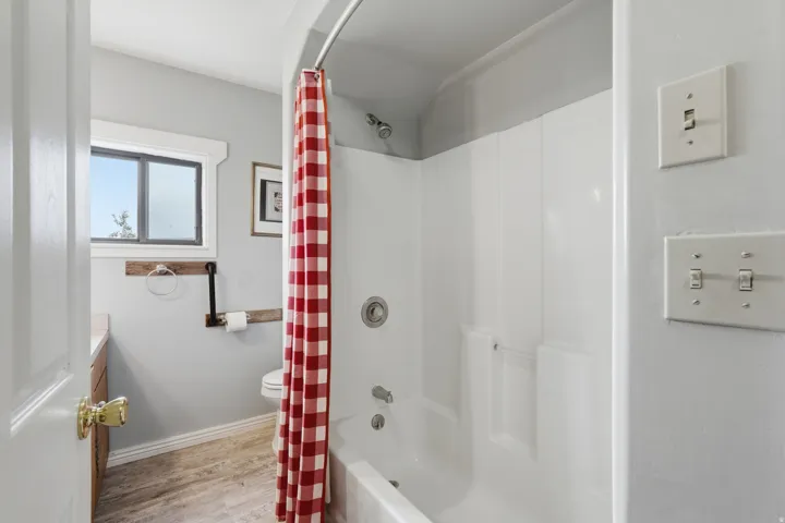 Bathroom featuring light wood-type flooring, vanity, and shower / bath combination with curtain
