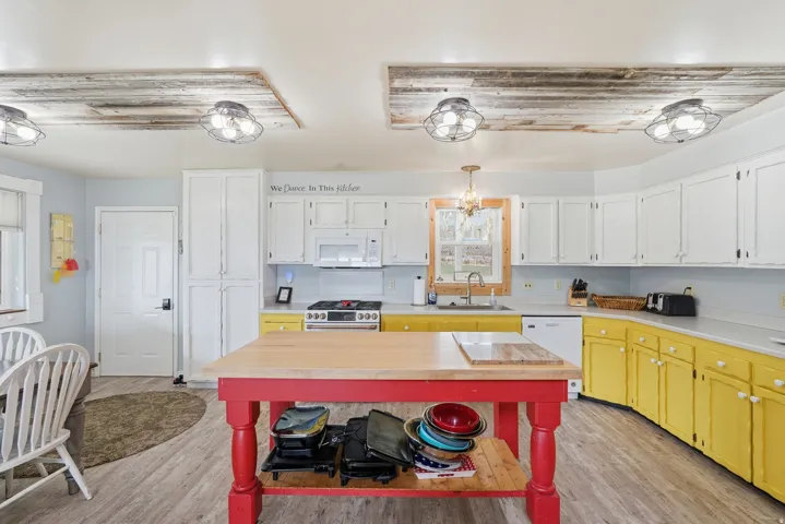 Kitchen with light countertops, white appliances, light wood-style flooring, and white cabinetry