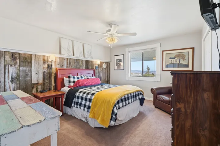 Carpeted bedroom featuring ceiling fan and baseboards