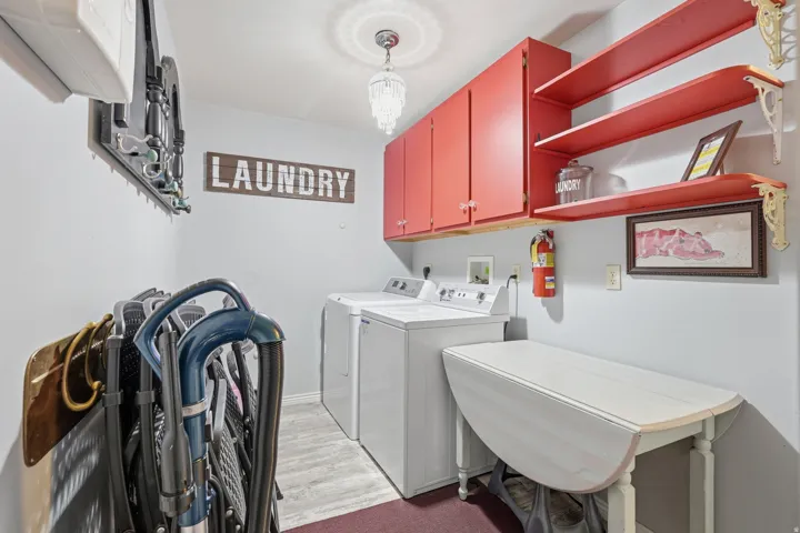 Laundry room with separate washer and dryer, cabinet space, light wood-style flooring, and hanging lights