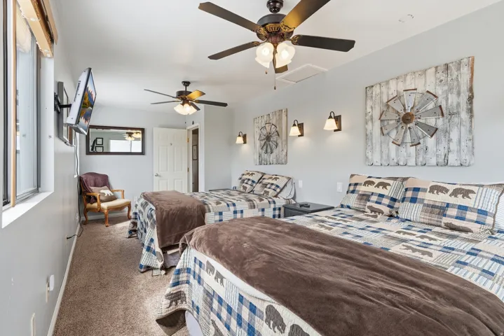 Carpeted bedroom with a ceiling fan and baseboards