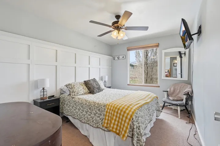 Bedroom with carpet floors, a ceiling fan, and a decorative wall