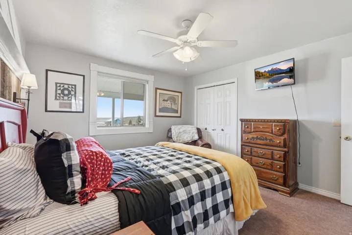 Carpeted bedroom with a ceiling fan and a closet