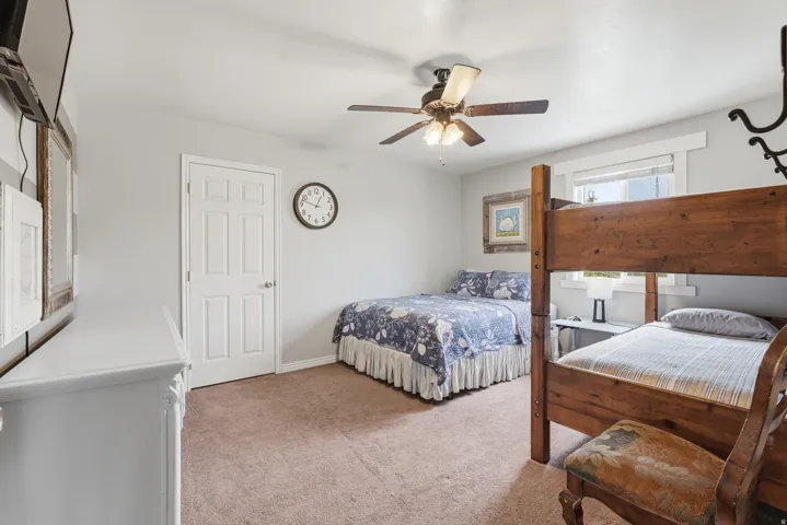 Bedroom with light colored carpet and a ceiling fan