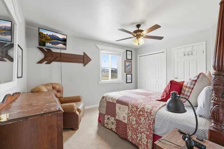 Bedroom with ceiling fan, light carpet, and two closets