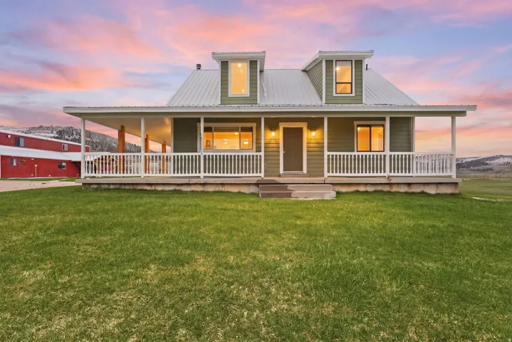 Farmhouse-style home with a porch, a yard, a metal roof, and a mountain view