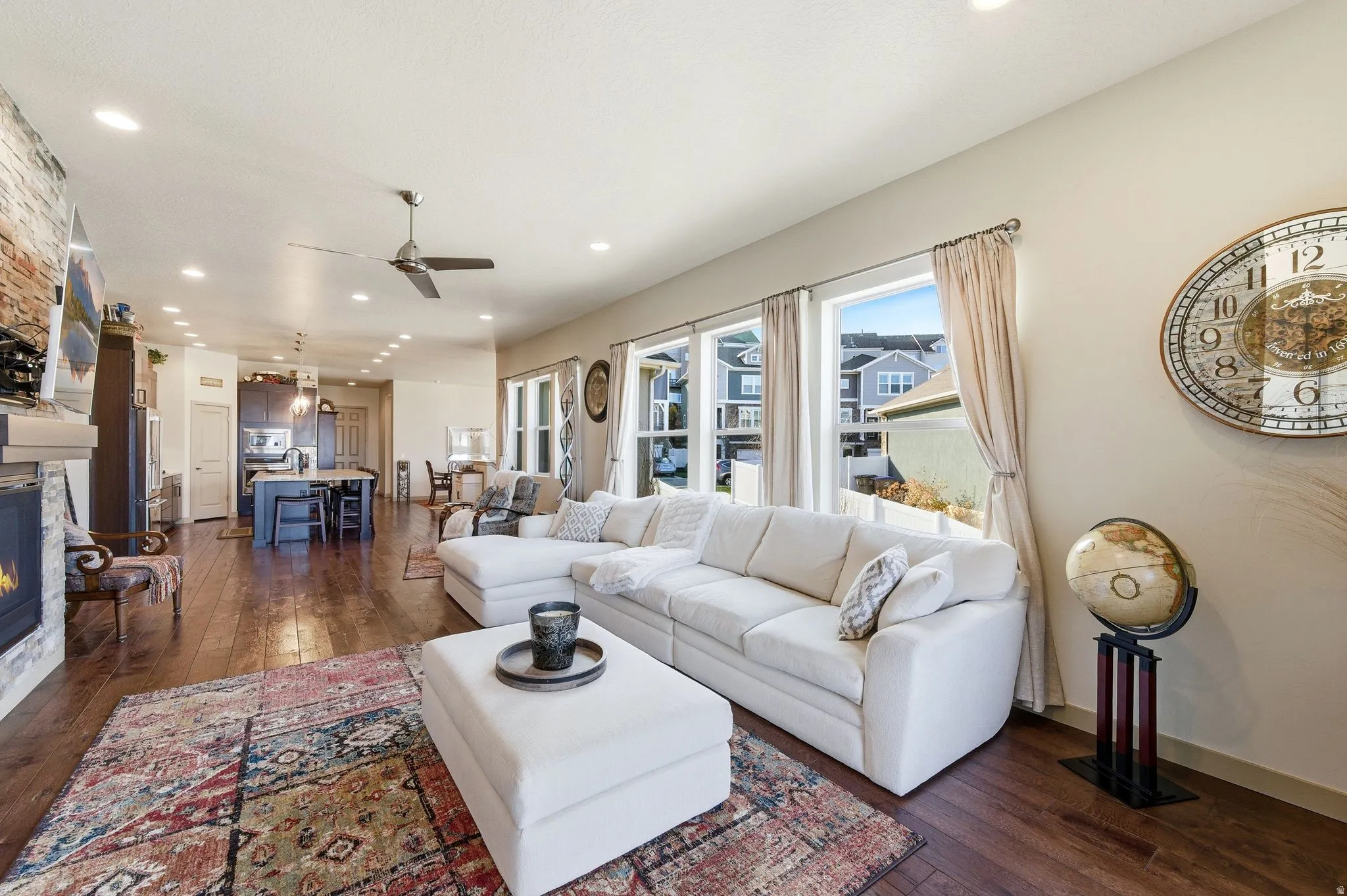 Living room with hardwood flooring, a fireplace, a ceiling fan, and recessed lighting.
