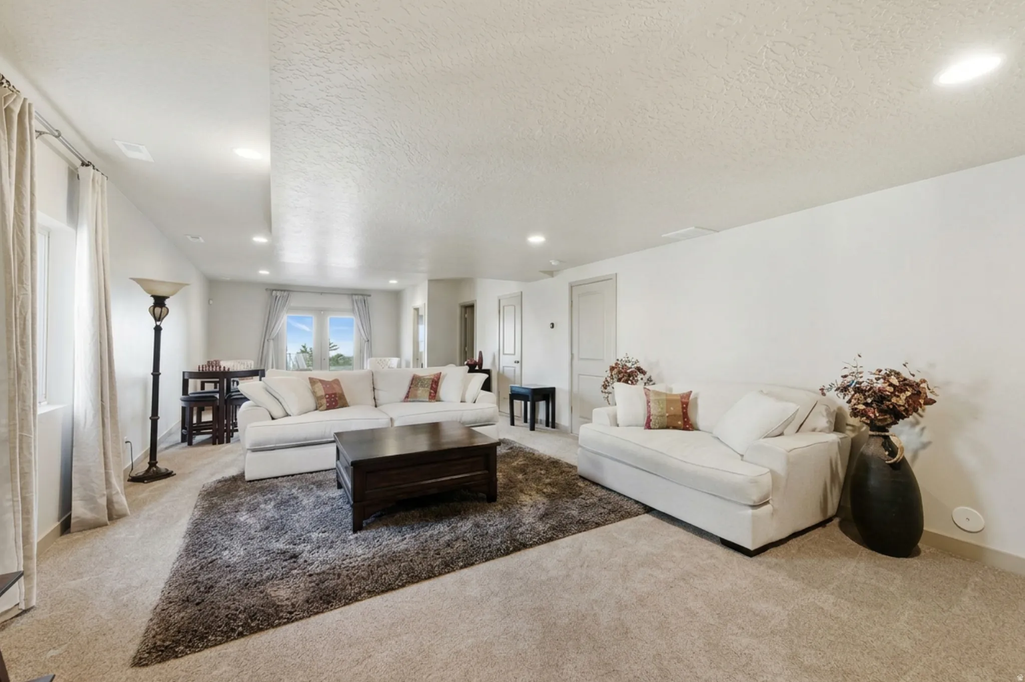 Large basement living room featuring carpet floors, a textured ceiling, and recessed lighting