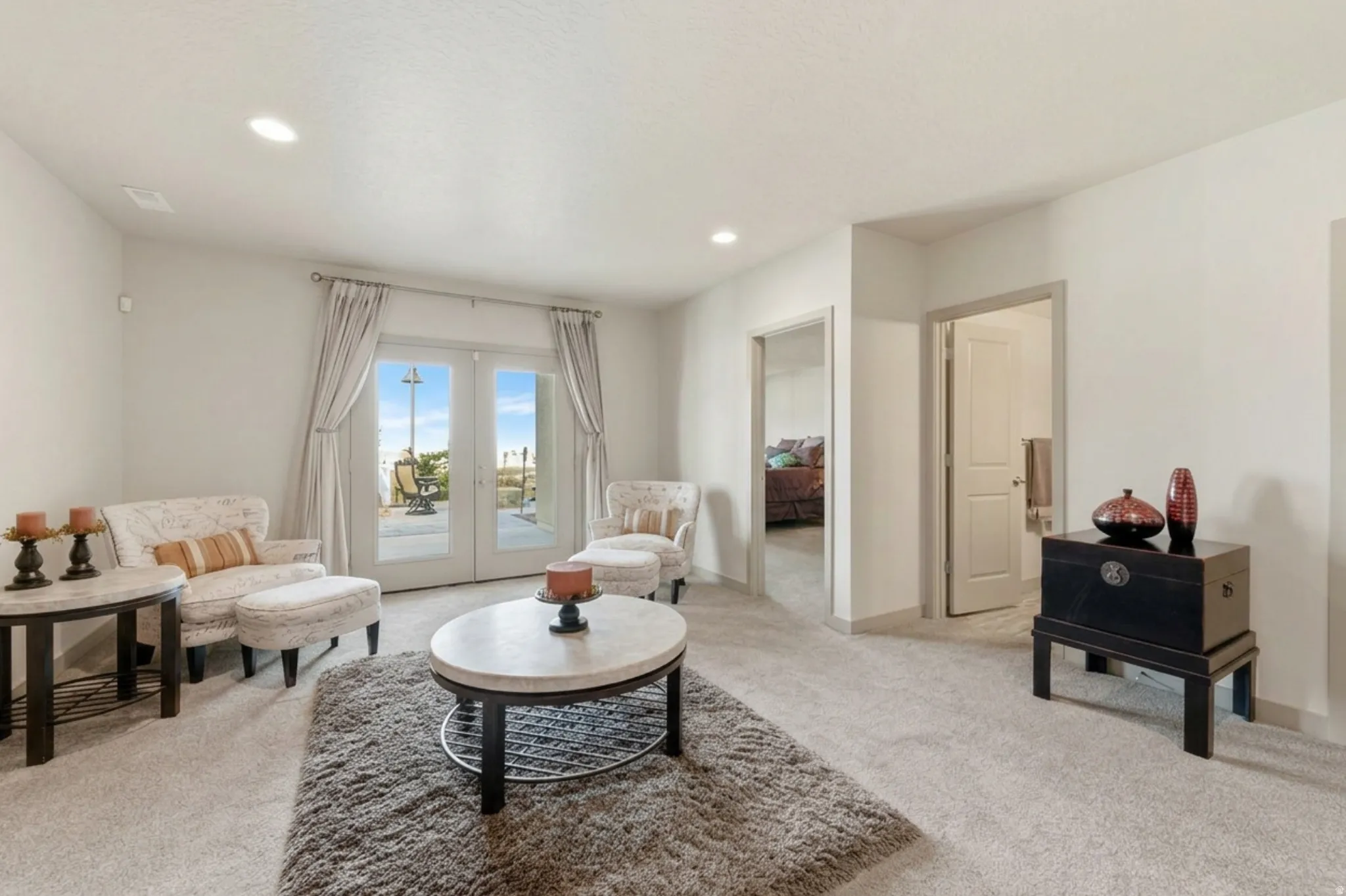 Basement living area with wall plumbed for kitchen, featuring french doors to back patio