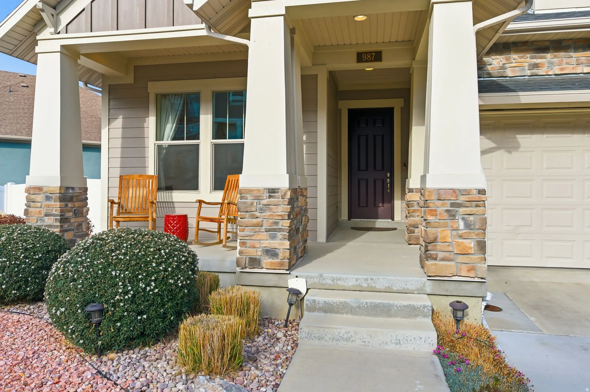 View of exterior entry with stone siding and covered porch