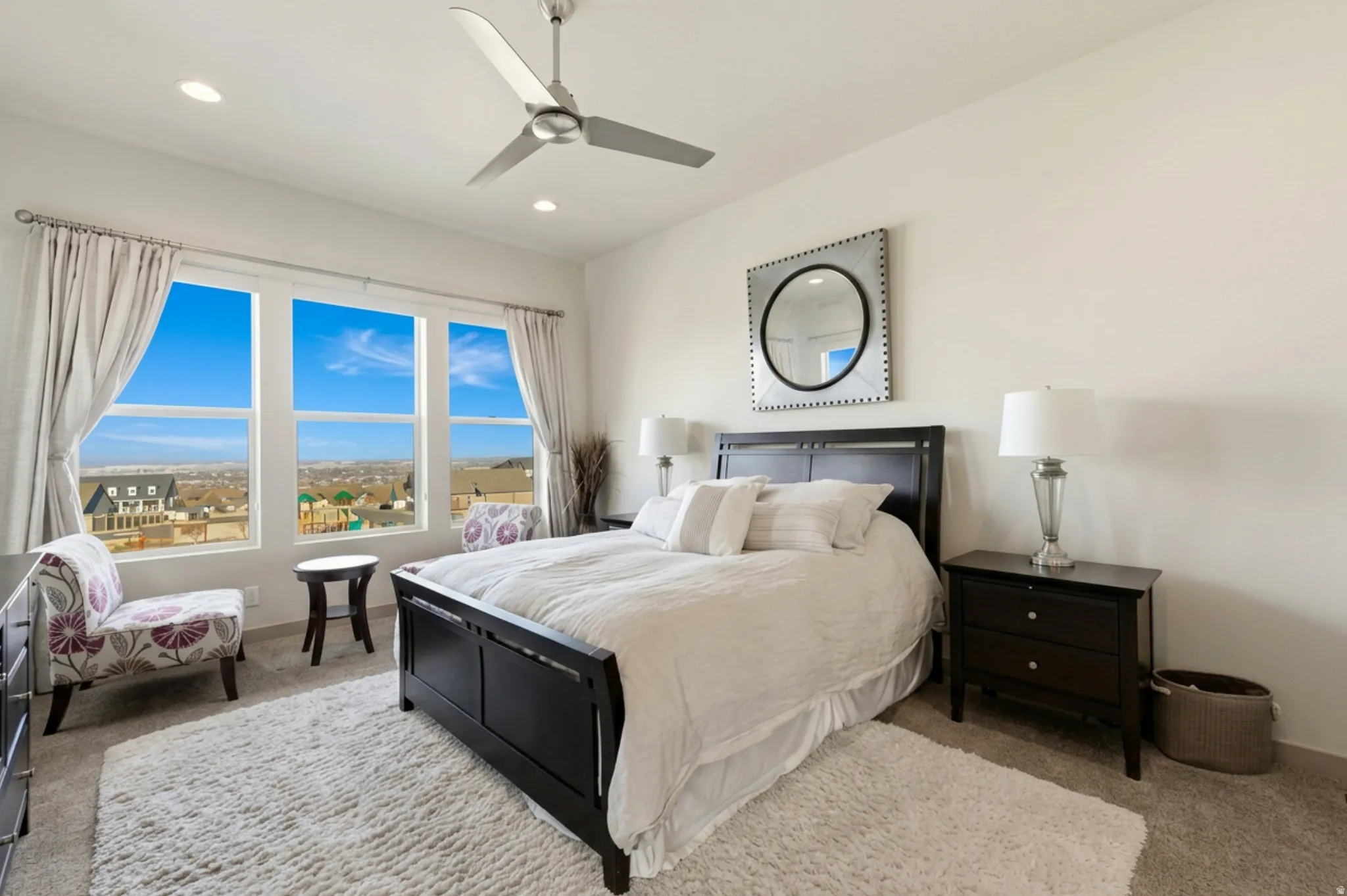 Primary bedroom featuring large windows, light carpet, a ceiling fan, recessed lighting, and drape