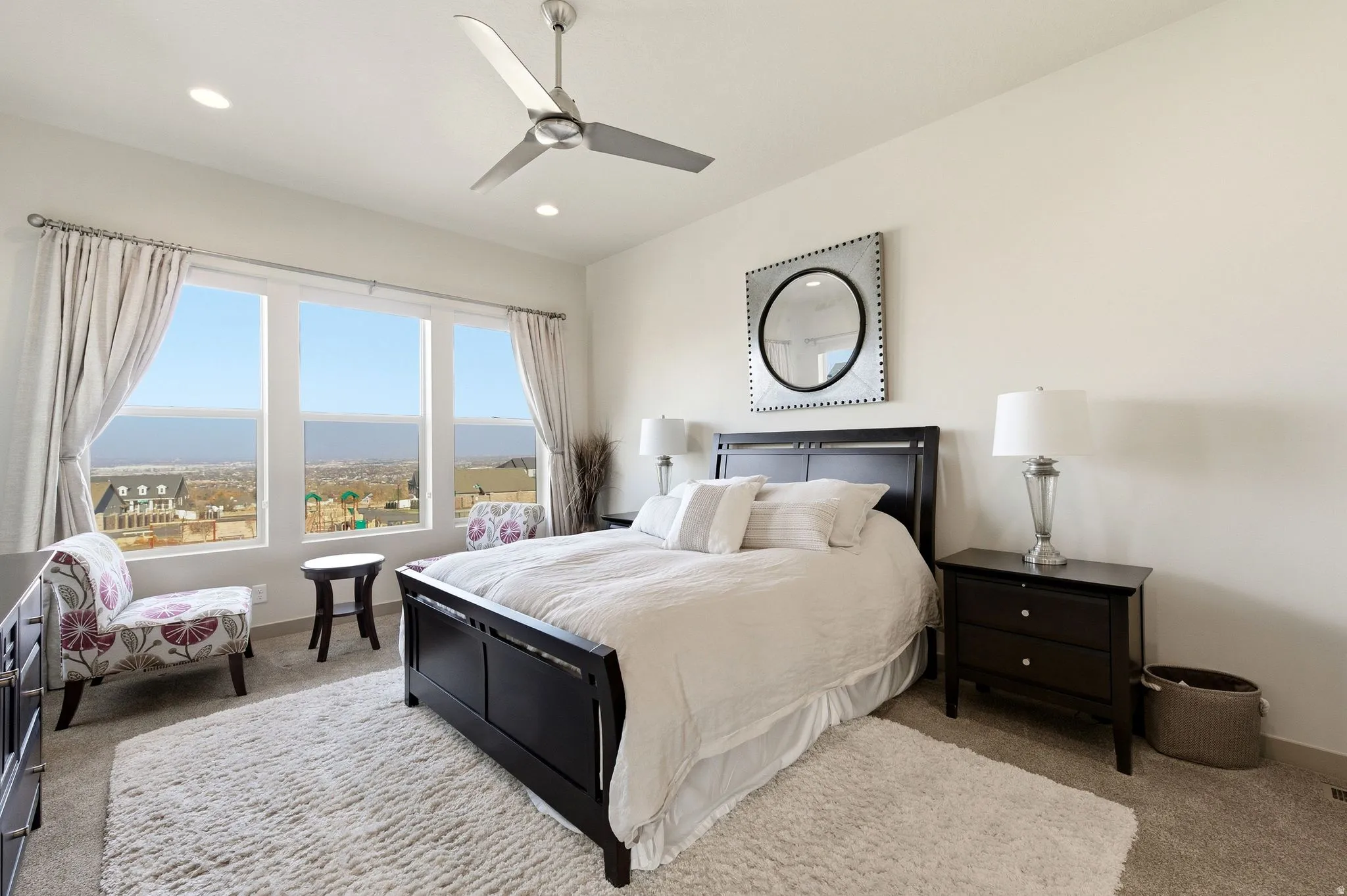 Primary bedroom featuring large windows, light carpet, a ceiling fan, recessed lighting, and drapes.