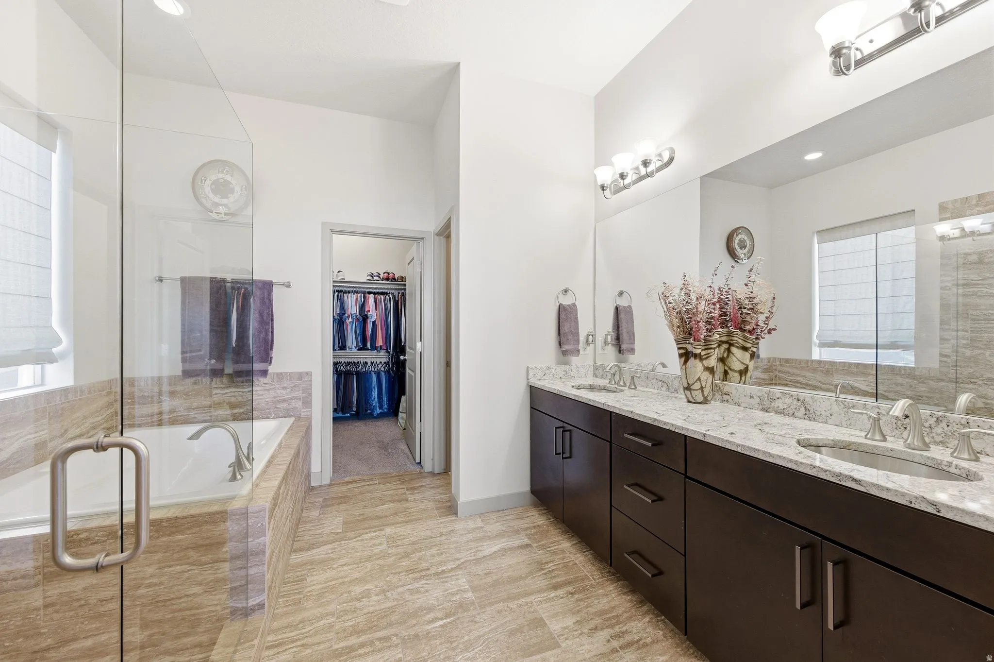 Primary ensuite bathroom featuring double vanity, a spacious closet, and separate garden tub and shower