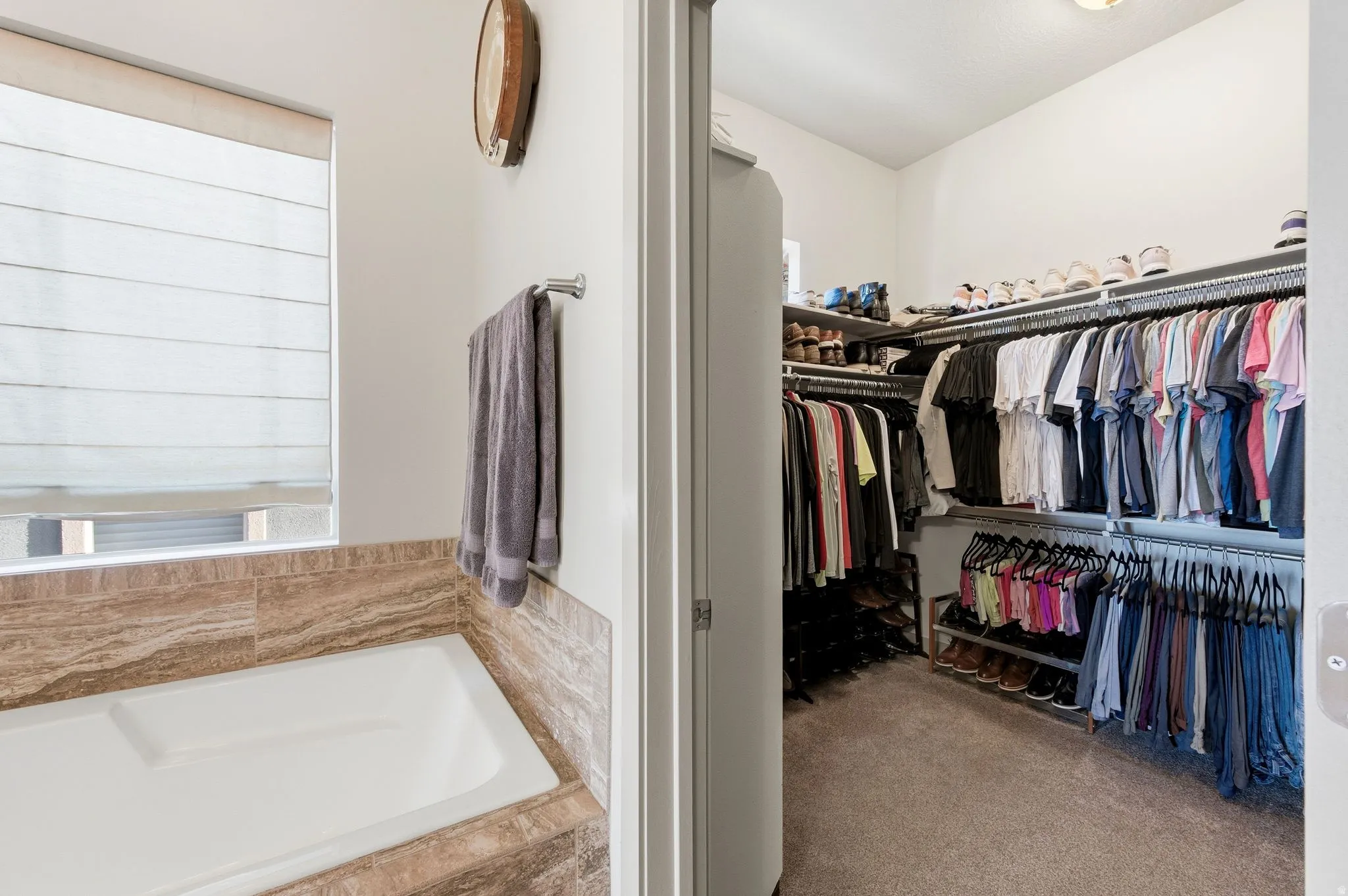 Primary walk-in closet featuring light colored carpet