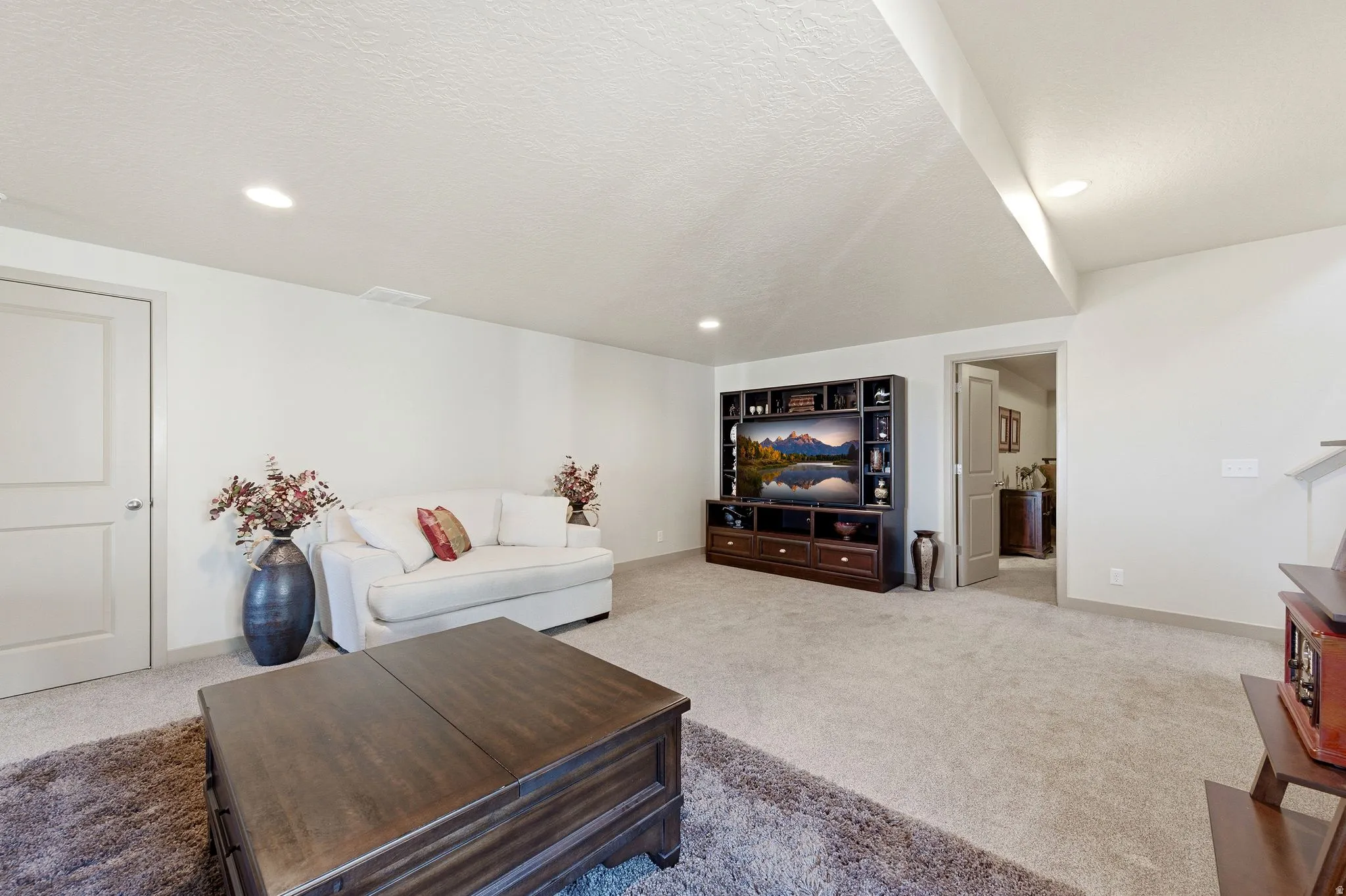 Large basement living room featuring carpet floors, a textured ceiling, and recessed lighting