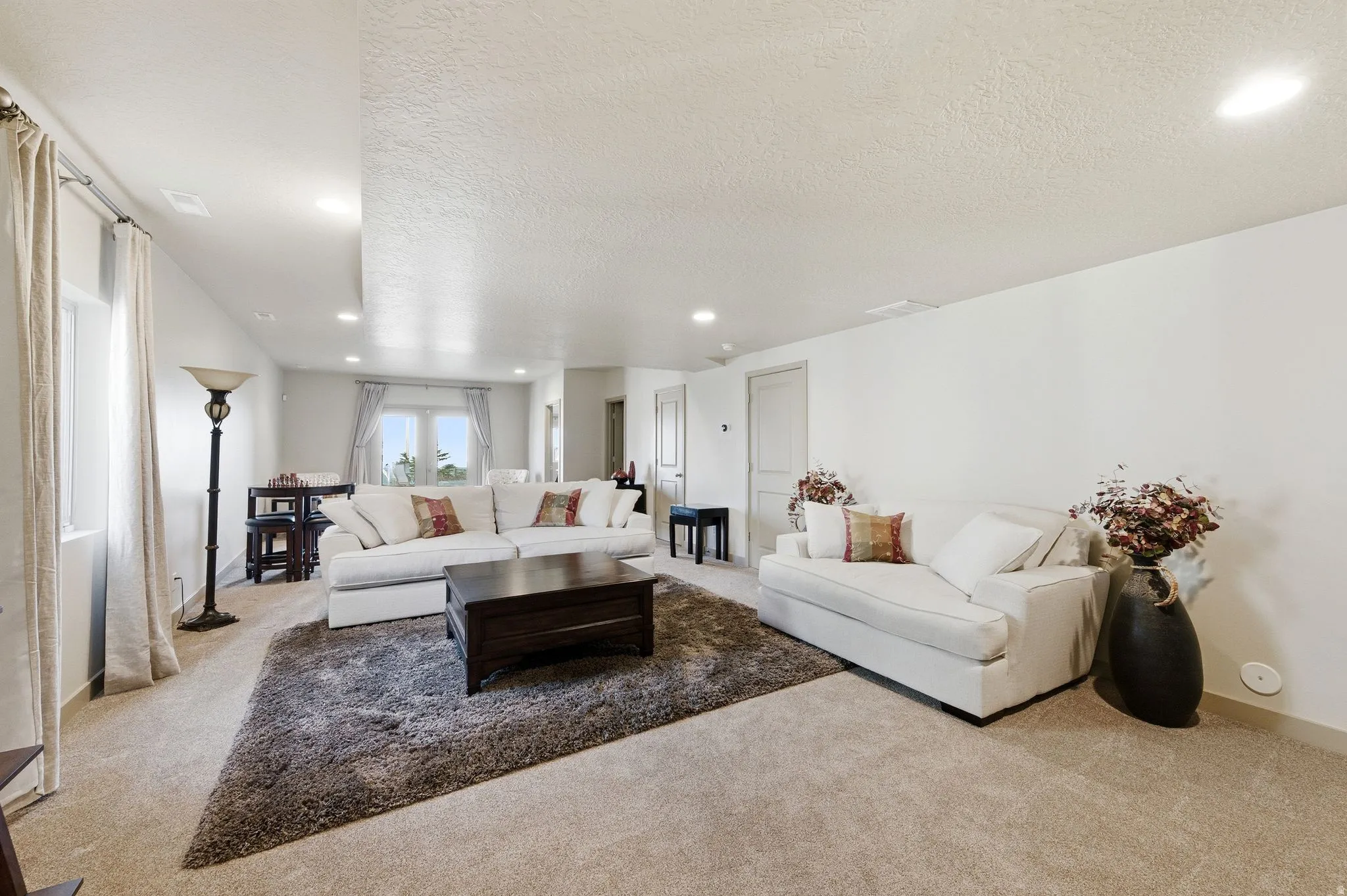 Large basement living room featuring carpet floors, a textured ceiling, and recessed lighting