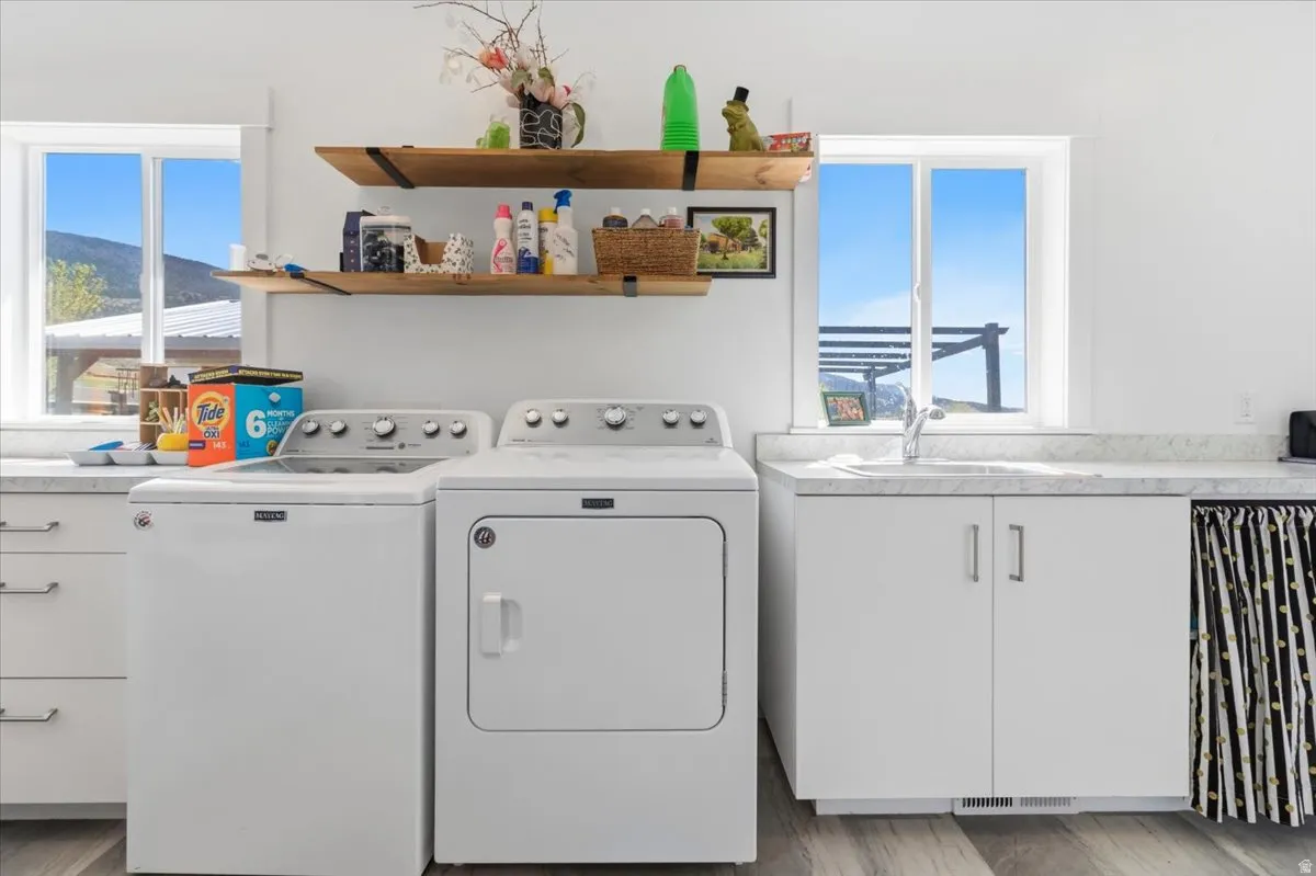 Laundry area with cabinet space, washing machine and dryer, and light wood-style floors