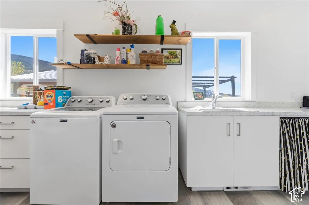 Laundry area with cabinet space, washing machine and dryer, and light wood-style floors
