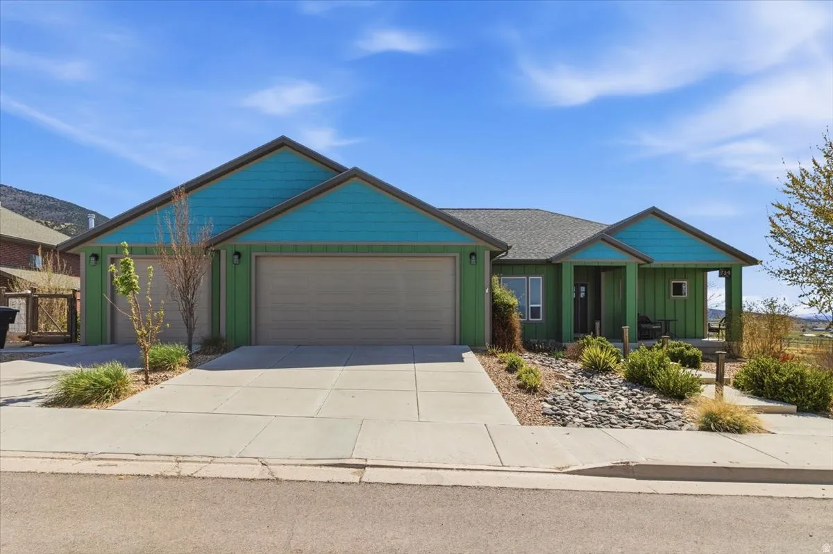 View of front of property featuring board and batten siding, driveway, an attached garage, and a porch