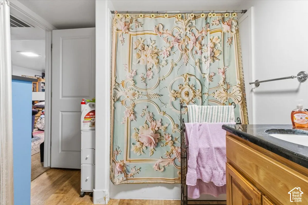 Full bath featuring vanity, a shower with curtain, and light wood-style flooring