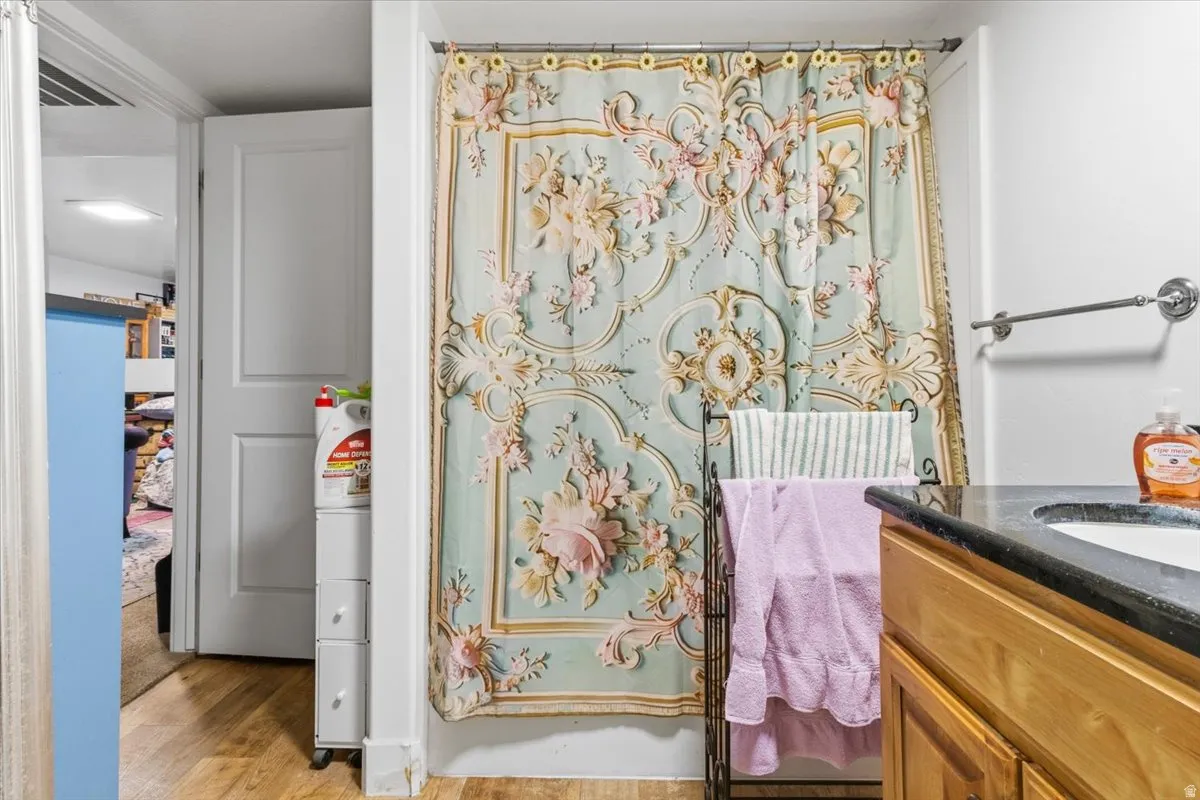 Full bath featuring vanity, a shower with curtain, and light wood-style flooring