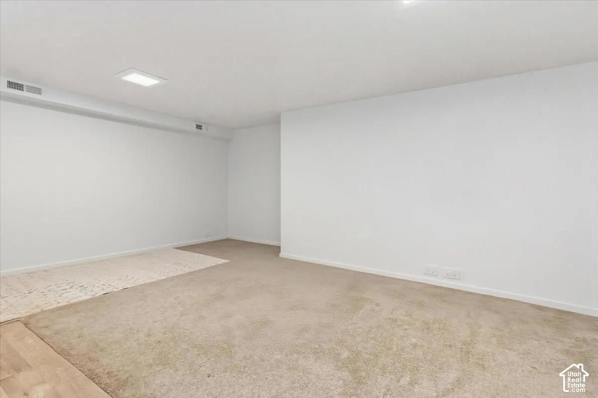 Unfurnished room featuring light carpet and baseboards