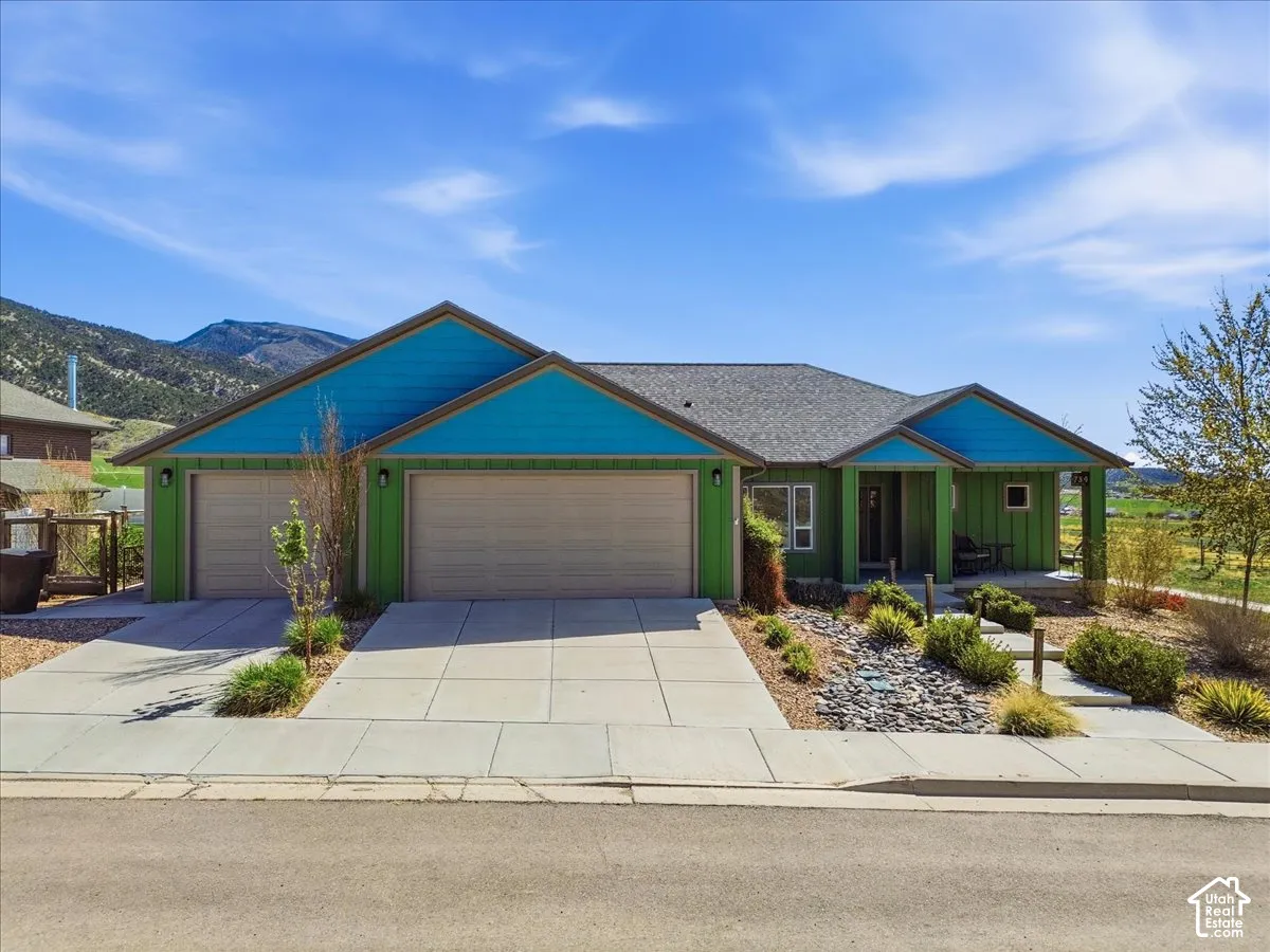 Ranch-style house with covered porch, driveway, an attached garage, board and batten siding, and a mountain view