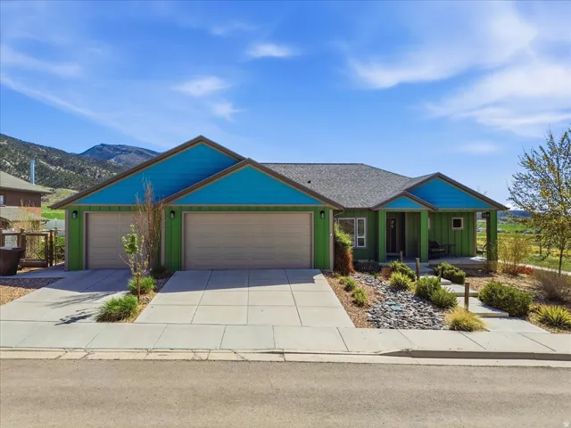 Ranch-style house with covered porch, driveway, an attached garage, board and batten siding, and a mountain view