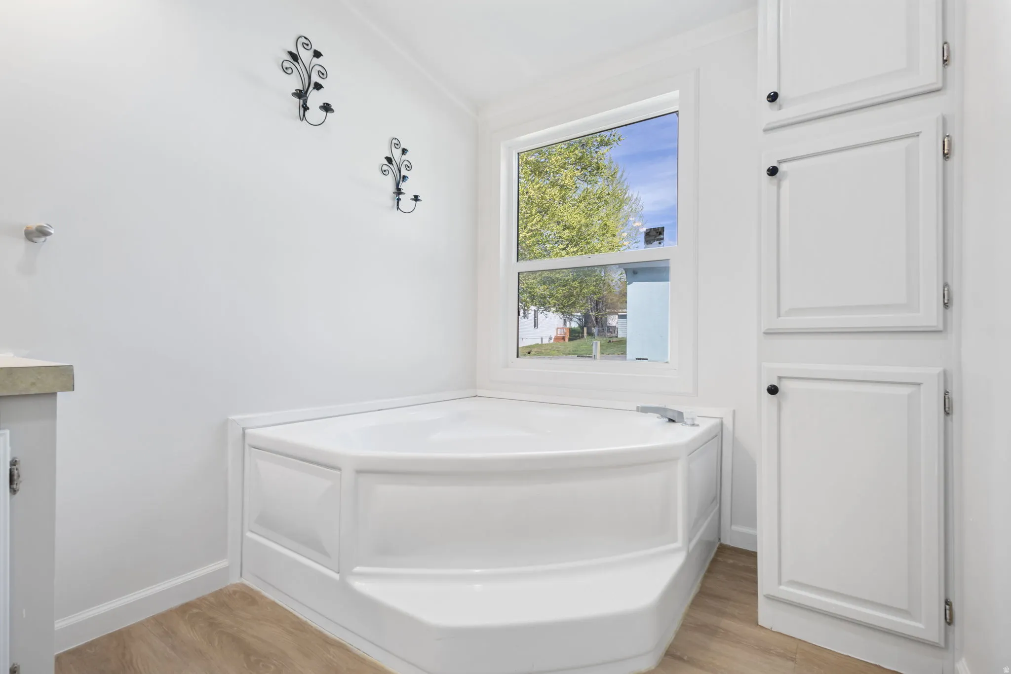 Bathroom featuring a garden tub, light wood-style flooring, and vanity