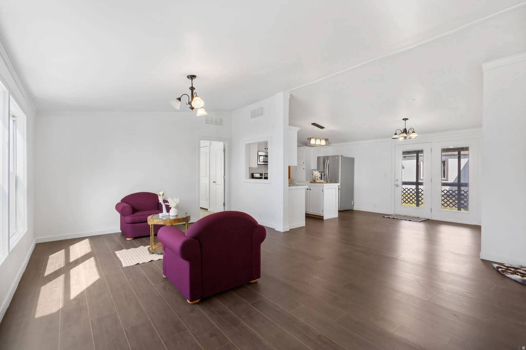 Living room featuring a chandelier, vaulted ceiling, dark wood-style floors, and crown molding