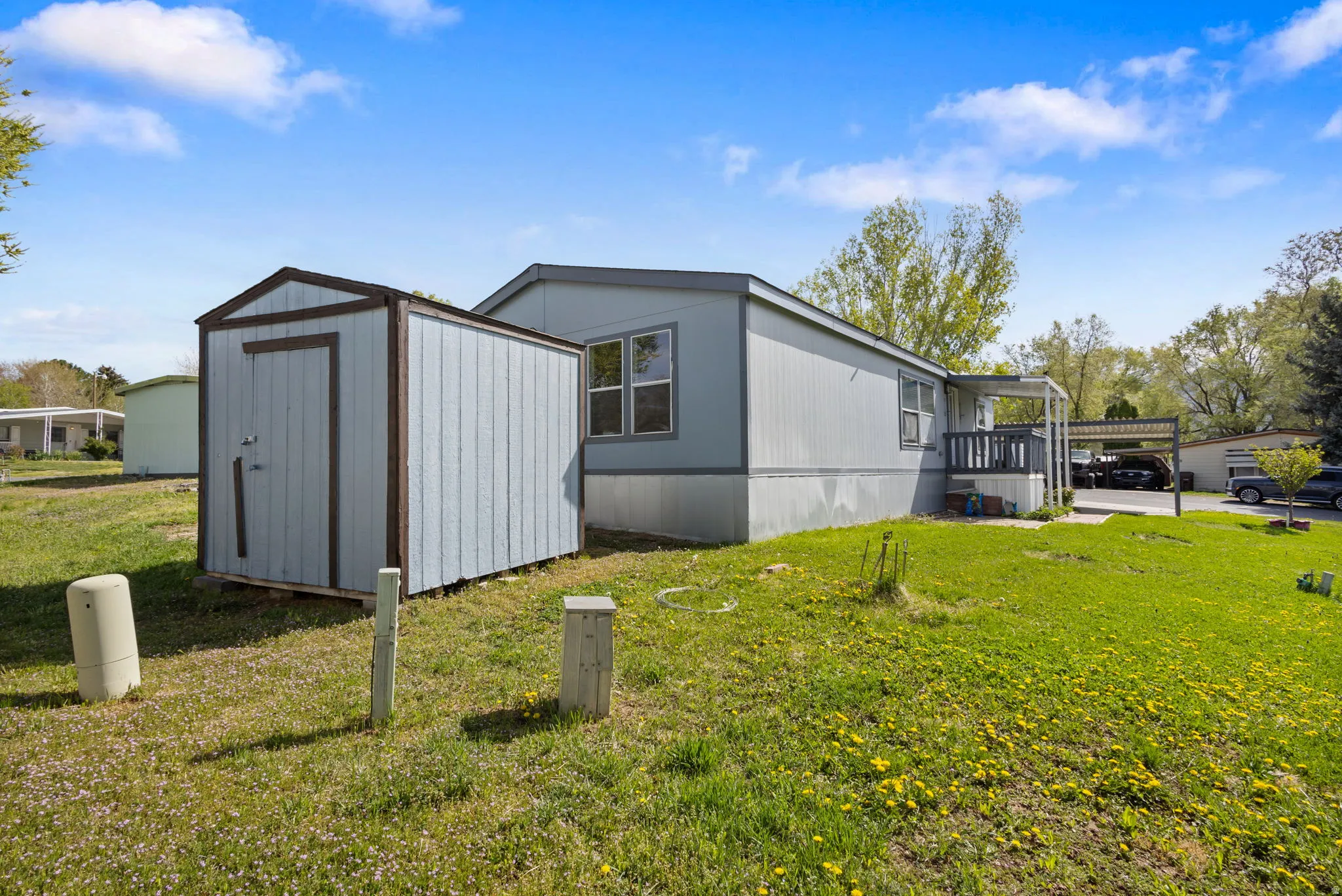View of side of property with a yard, a shed, and a carport