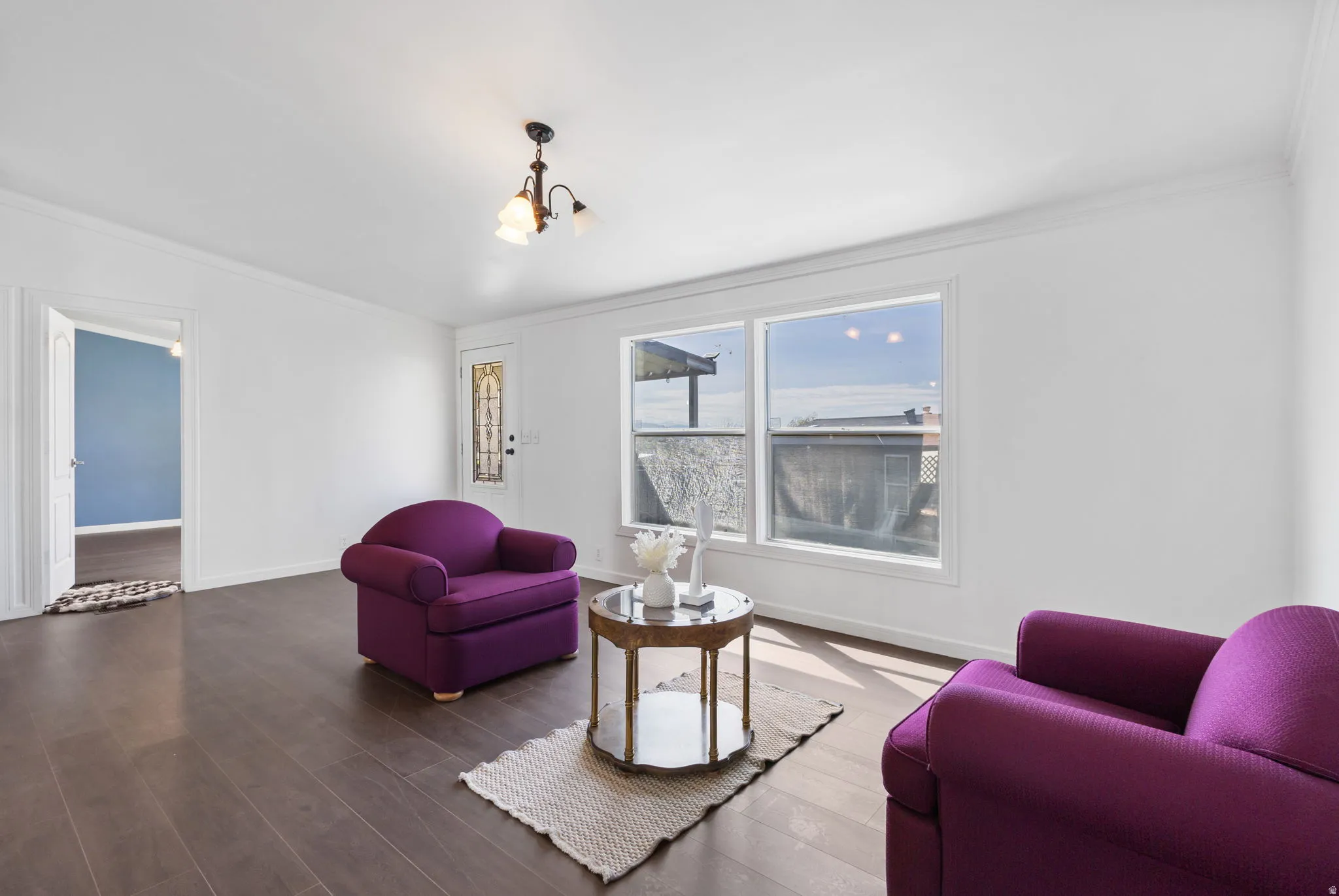 Living room featuring wood finished floors, crown molding, and hanging lights