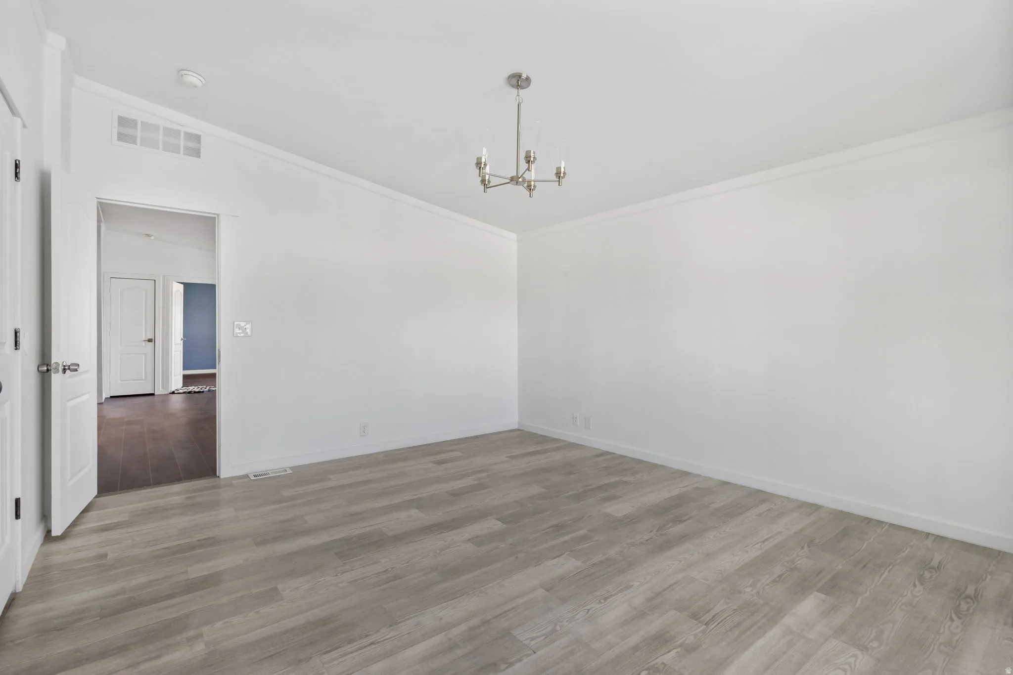 Unfurnished dining area featuring ornamental molding, light wood-style floors, hanging lights, and vaulted ceiling