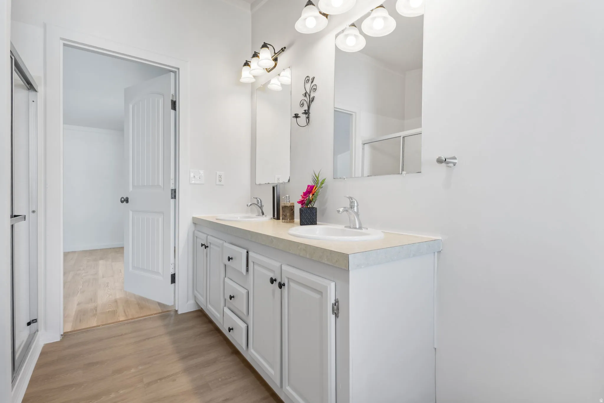Full bath featuring double vanity and light wood-type flooring